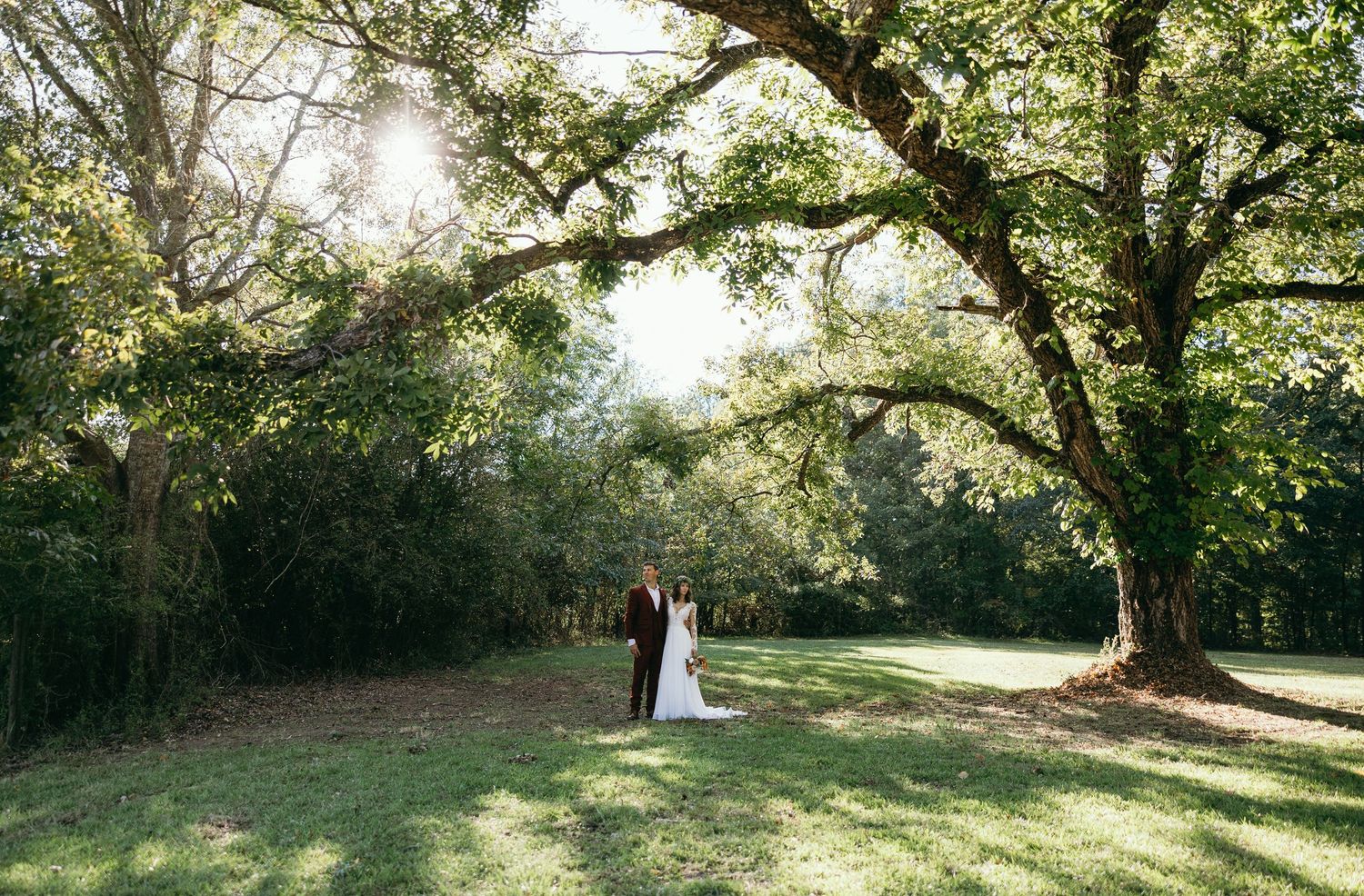 Artistic golden hour wedding portrait of the couple embracing under a massive oak tree at an outdoor wedding venue in Chattanooga, TN.