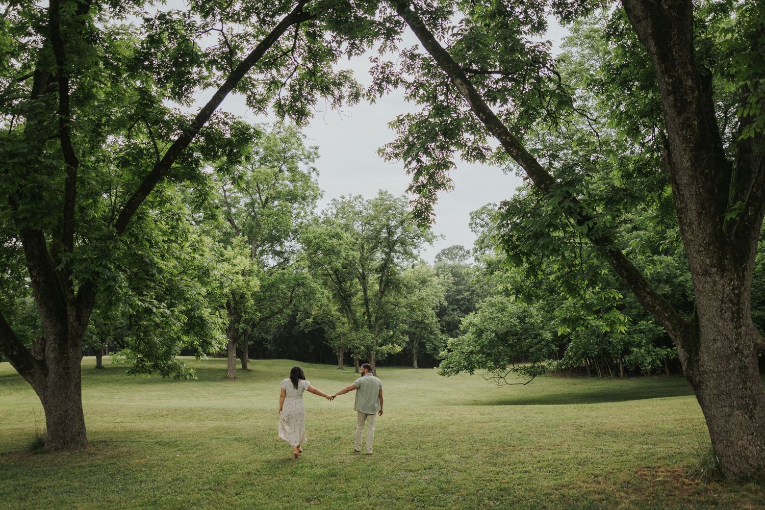 Artistic photography Couple's Engagement Session in a quiet green field with dappled light under the trees. Chattanooga, TN wedding