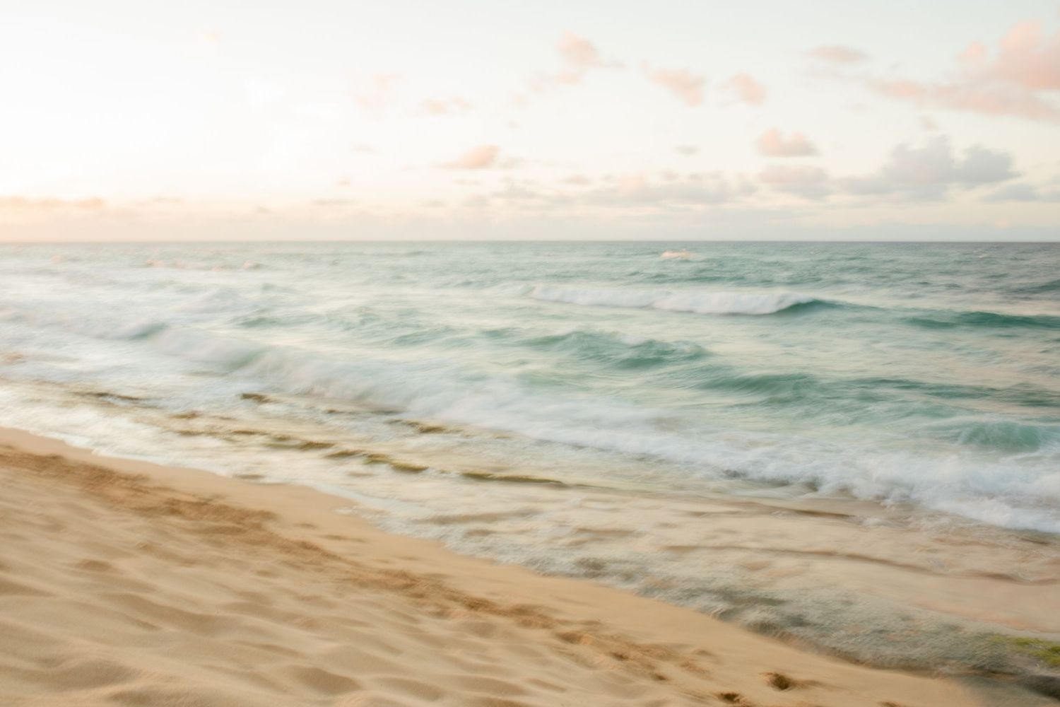 Fine Art Wedding Film establishing shot of soft ocean waves rolling onto a golden sand beach at sunset. Perfect for a destination elopement.