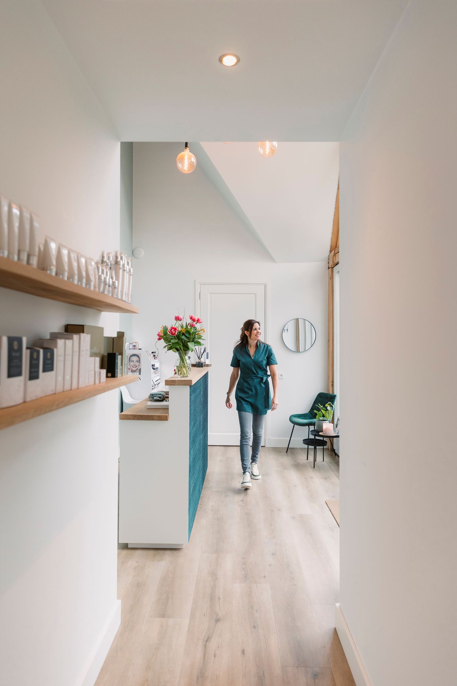 Modern white hallway with wooden floors and built-in shelving displaying white decorative items.