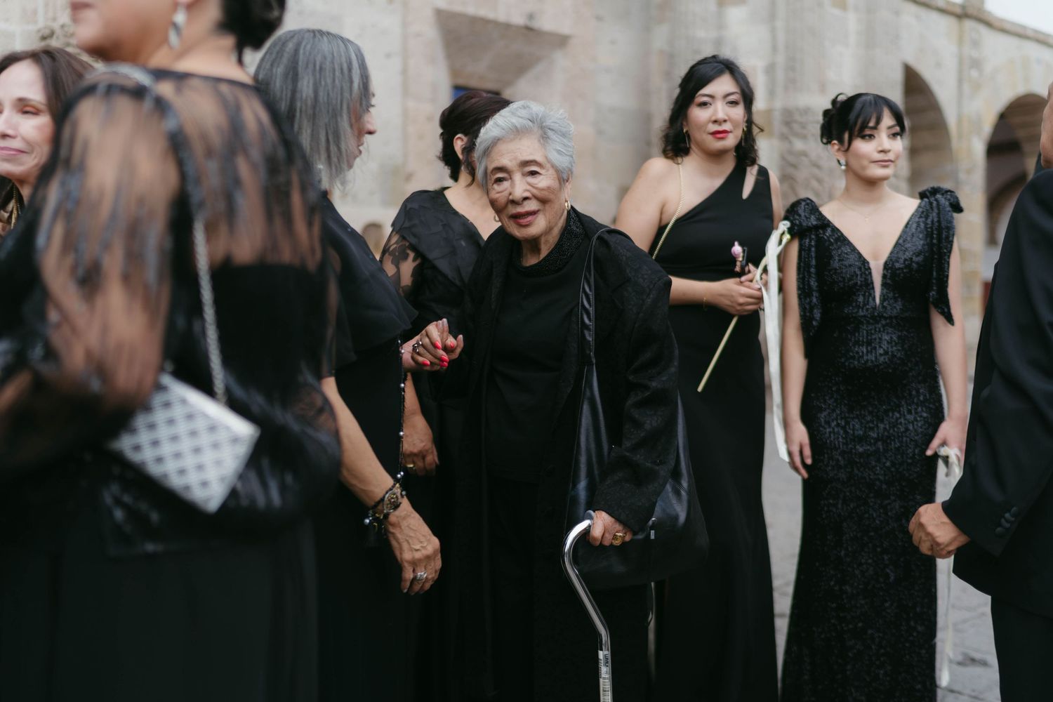 Wedding guests in black attire celebrating outdoors.
