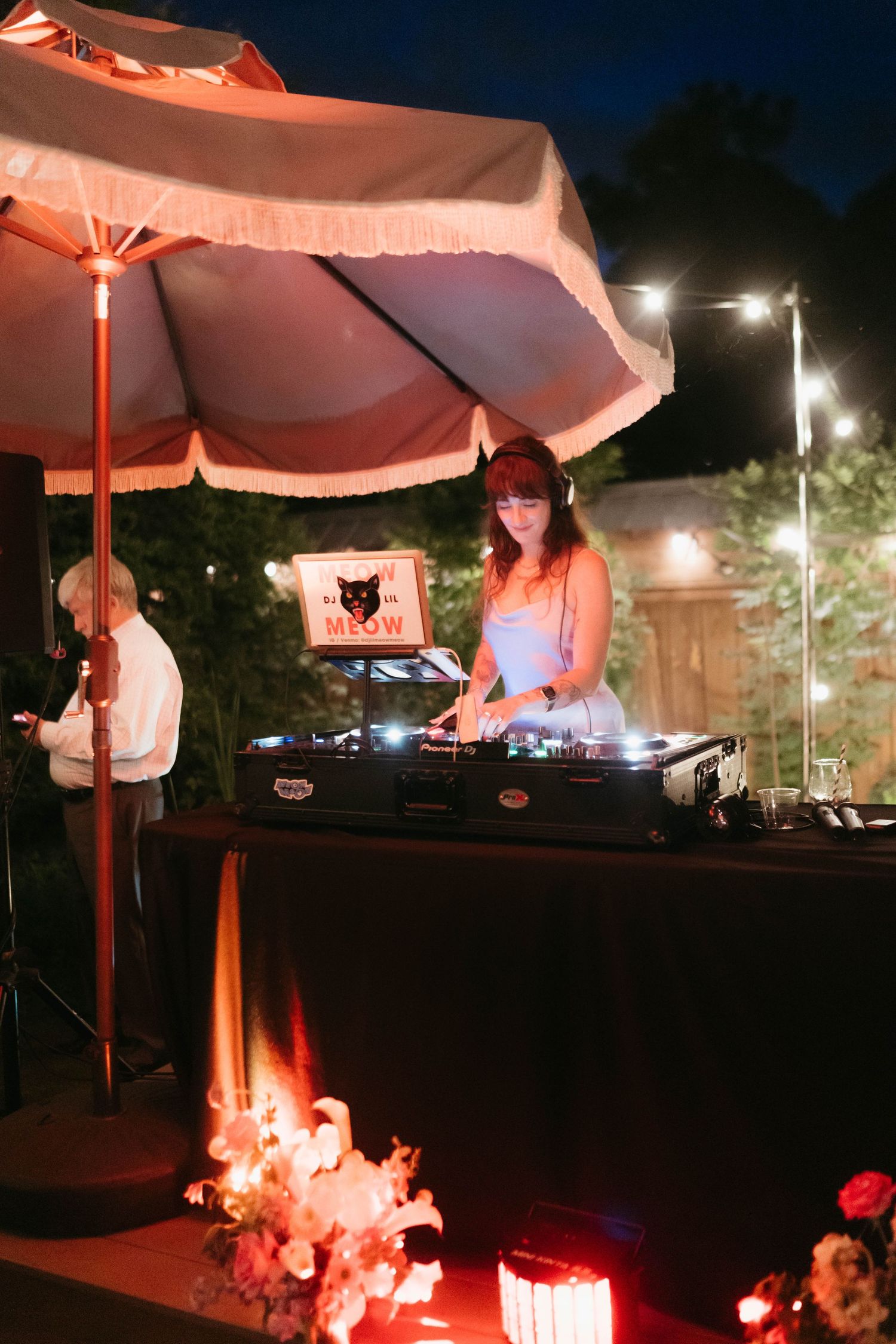 DJ booth setup with red lighting at an outdoor nighttime event.