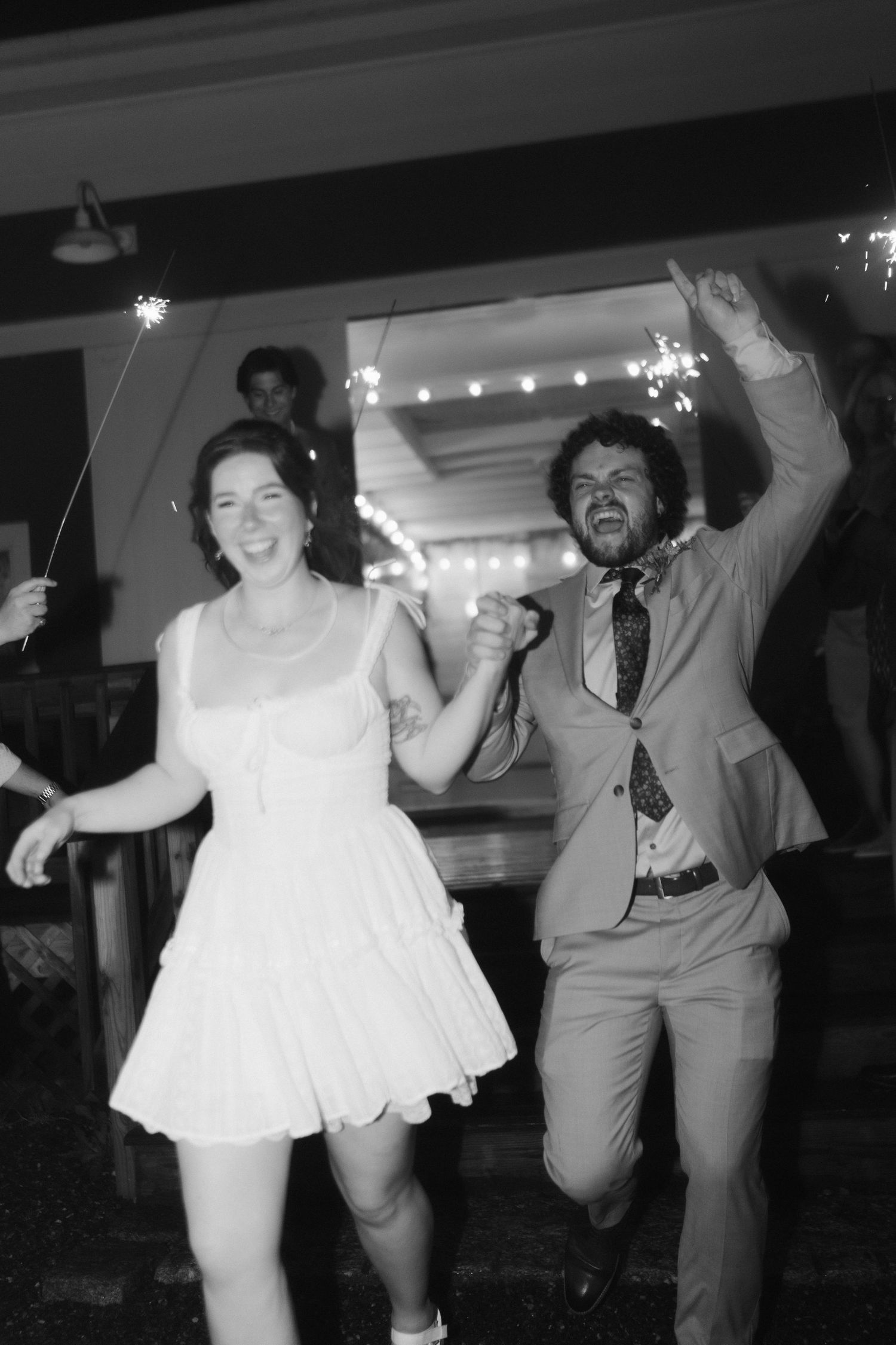Wedding party dancing and celebrating in a dimly lit reception venue.