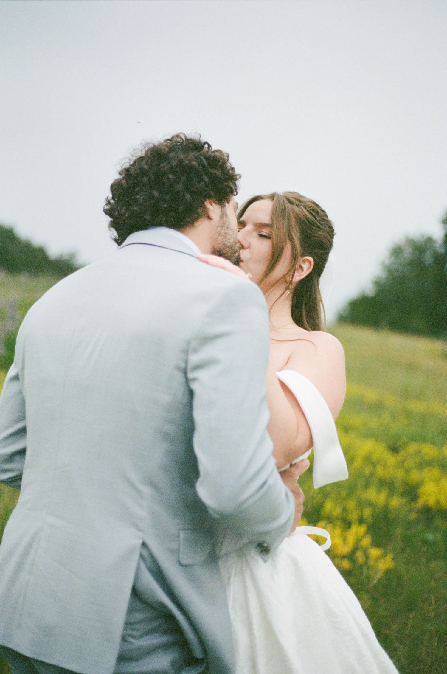 A romantic wedding moment captured in a wildflower meadow during golden hour.