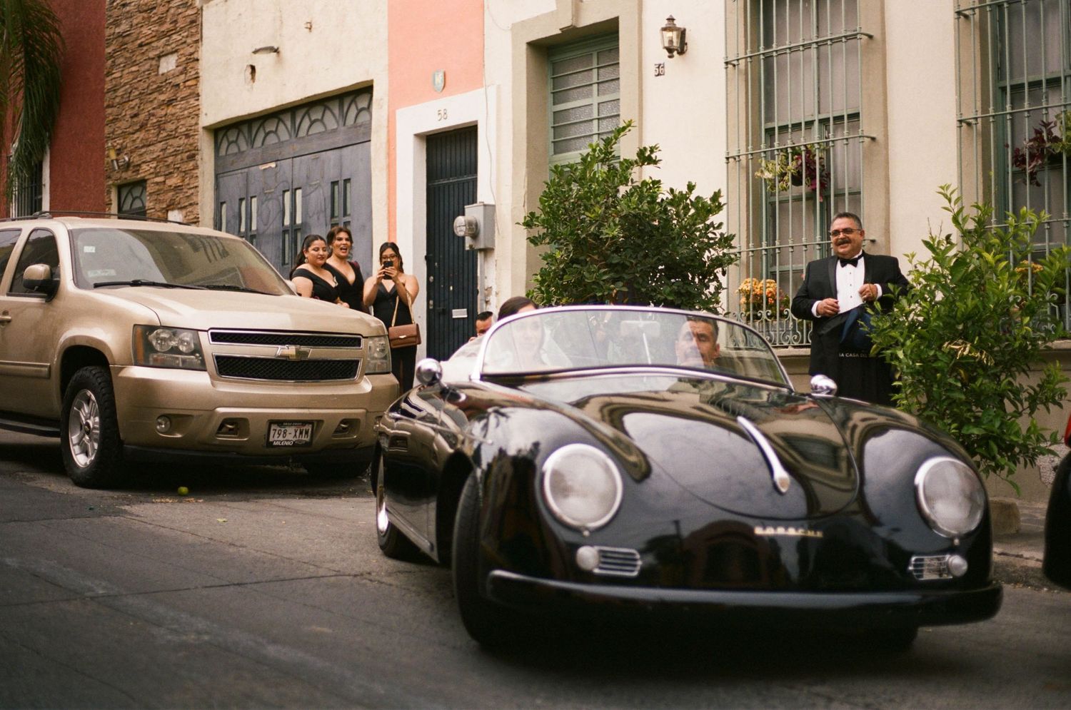 A vintage black Porsche convertible parked on a street lined with colorful colonial buildings.