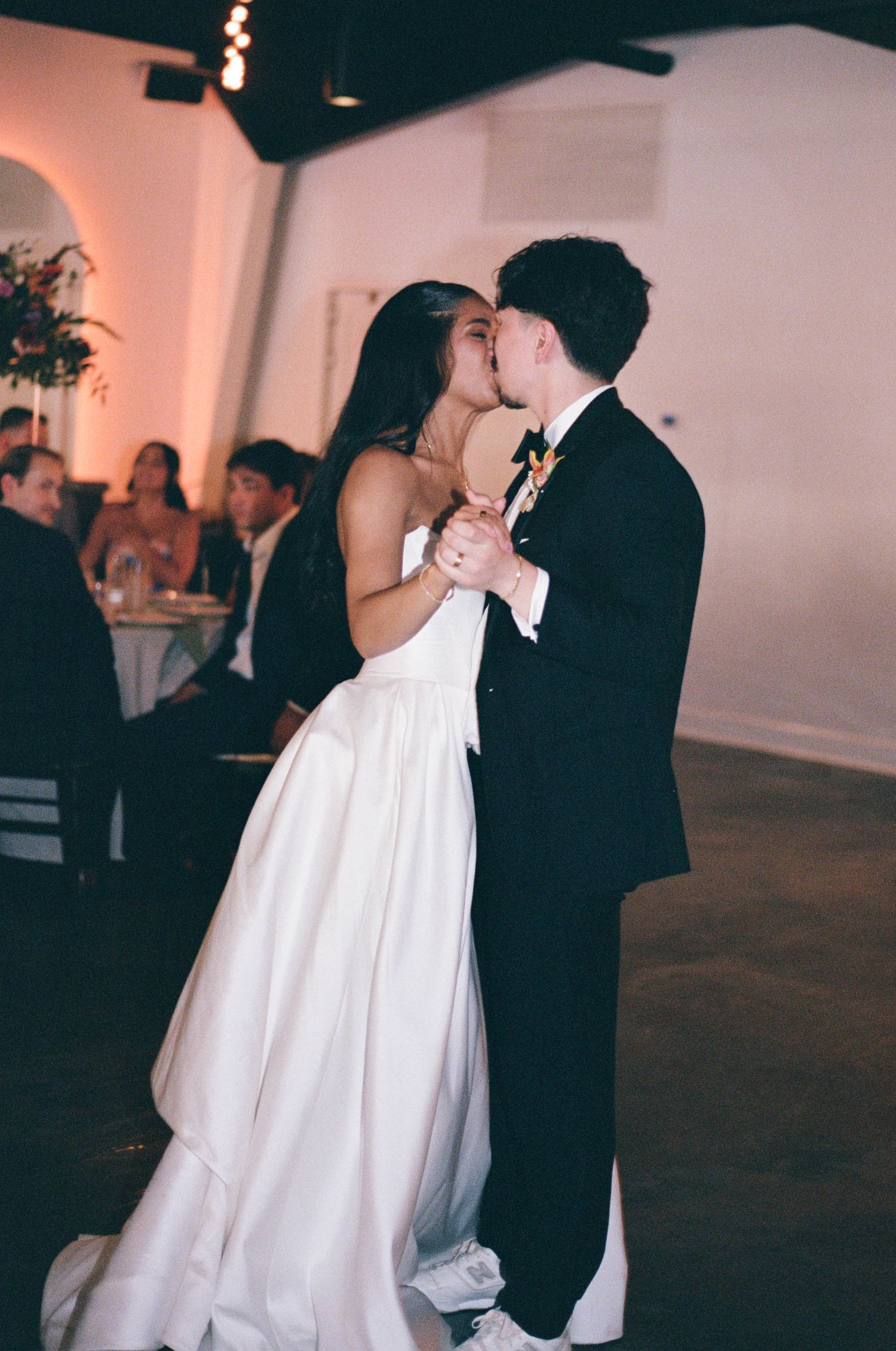 Wedding couple shares their first dance in a dimly lit reception venue.