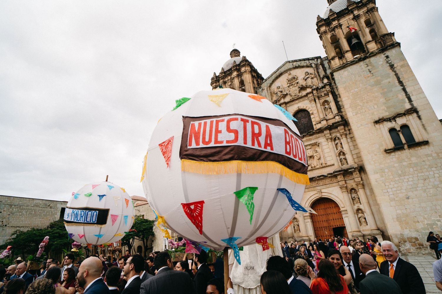 Historic Mexican church facade with celebratory balloons and gathered crowd during a wedding.