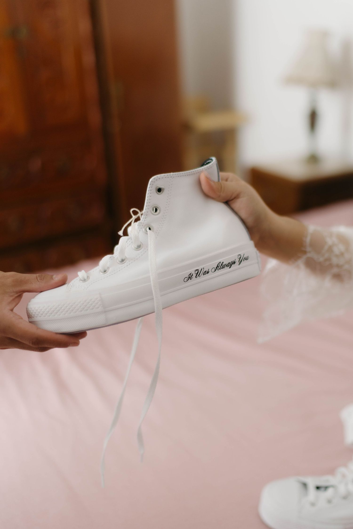 White sneakers displayed on pink fabric in detail shots.