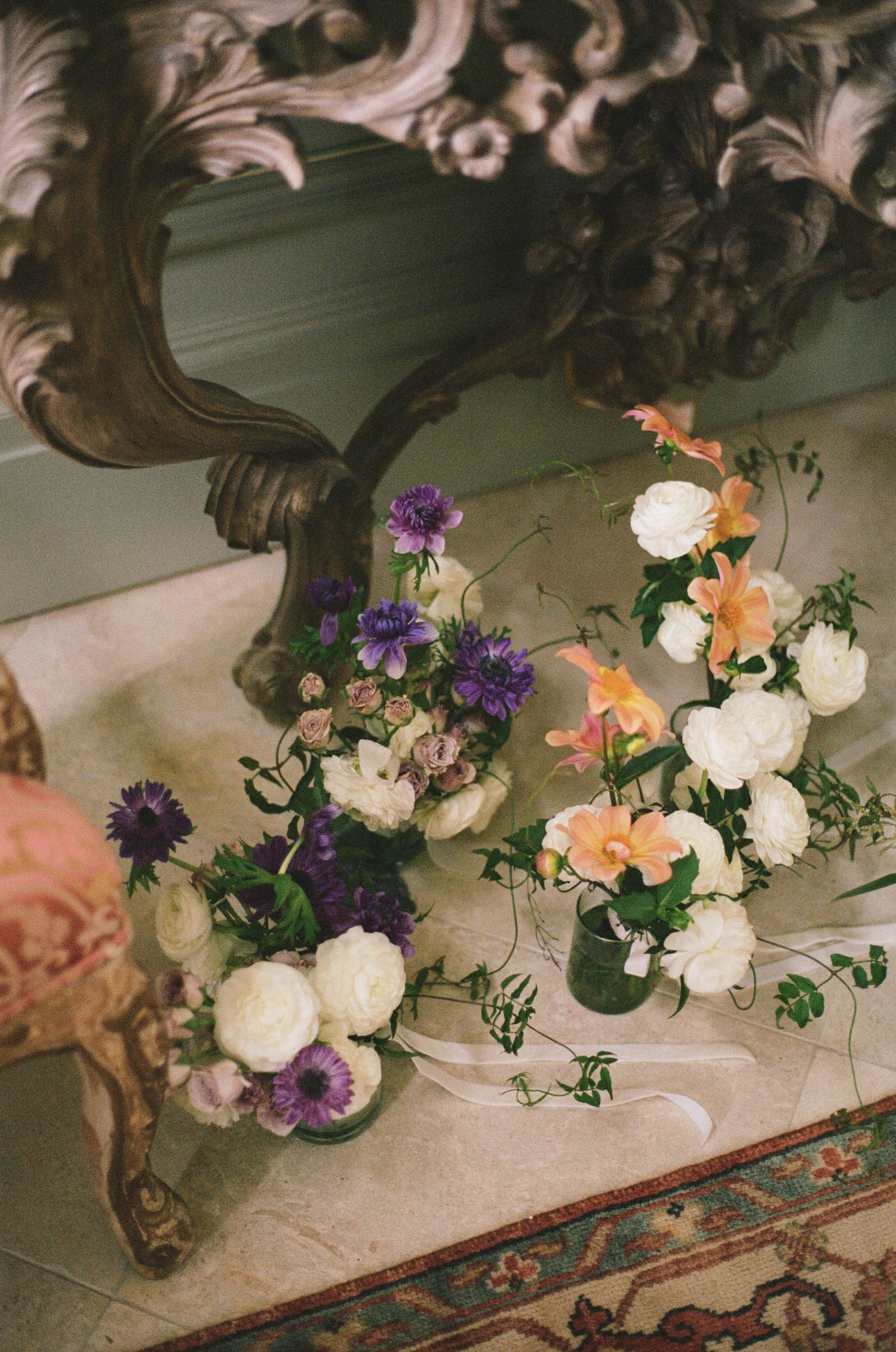 Beautiful wedding floral arrangements of white, purple, and peach flowers displayed on an ornate marble table.