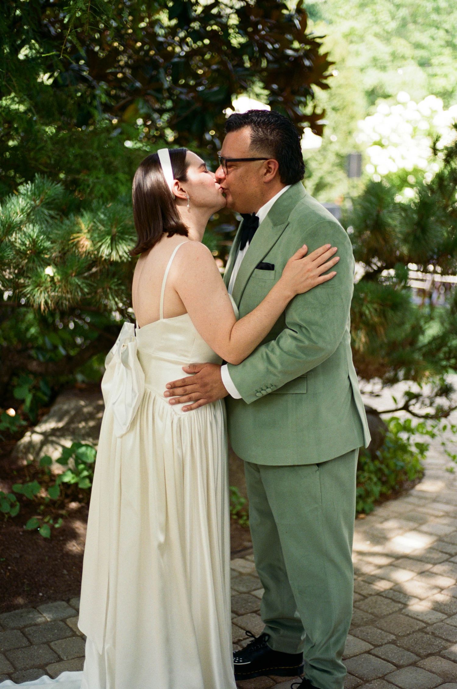 Romantic moment captured in garden setting with stone pathway and natural lighting.