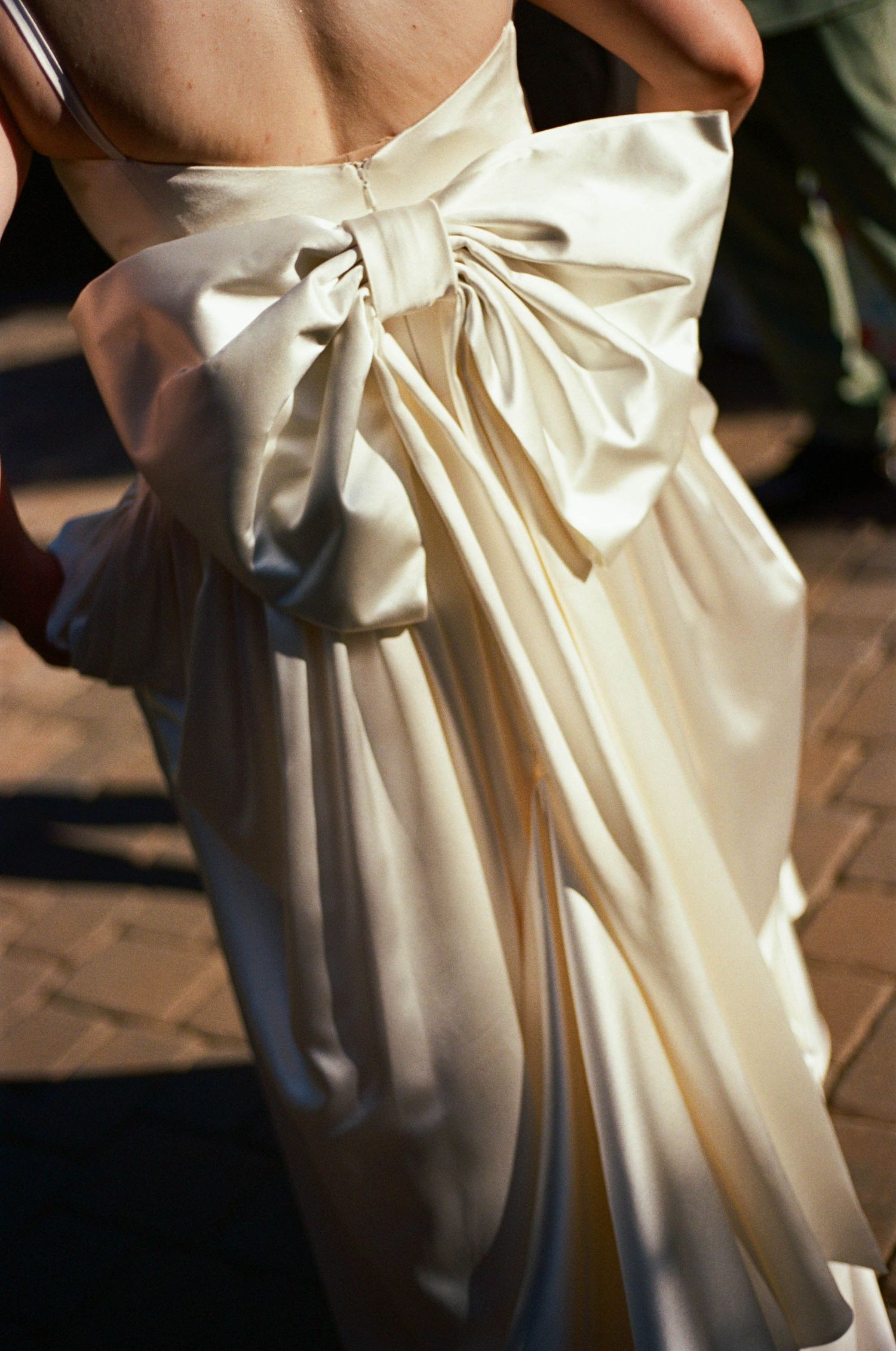Close-up detail of an elegant white wedding dress bow on the back.