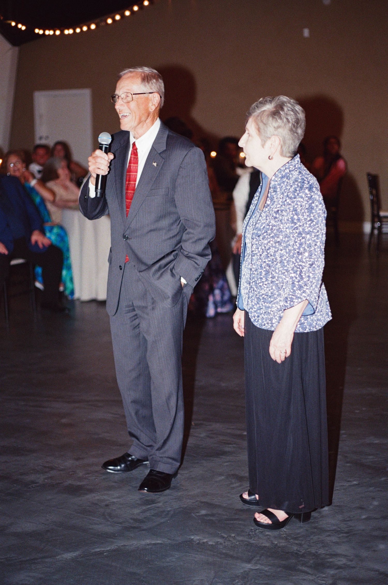 Wedding guests dance on a dark reception floor under string lights.