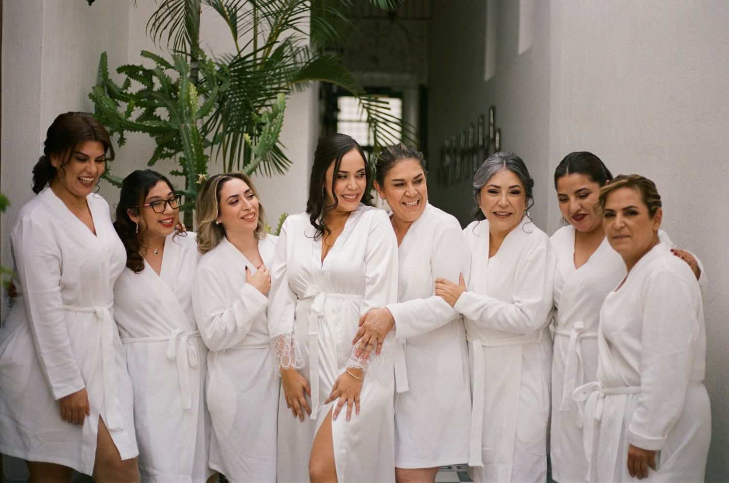 A group wearing white robes stands together in a hallway with decorative tiled floors.