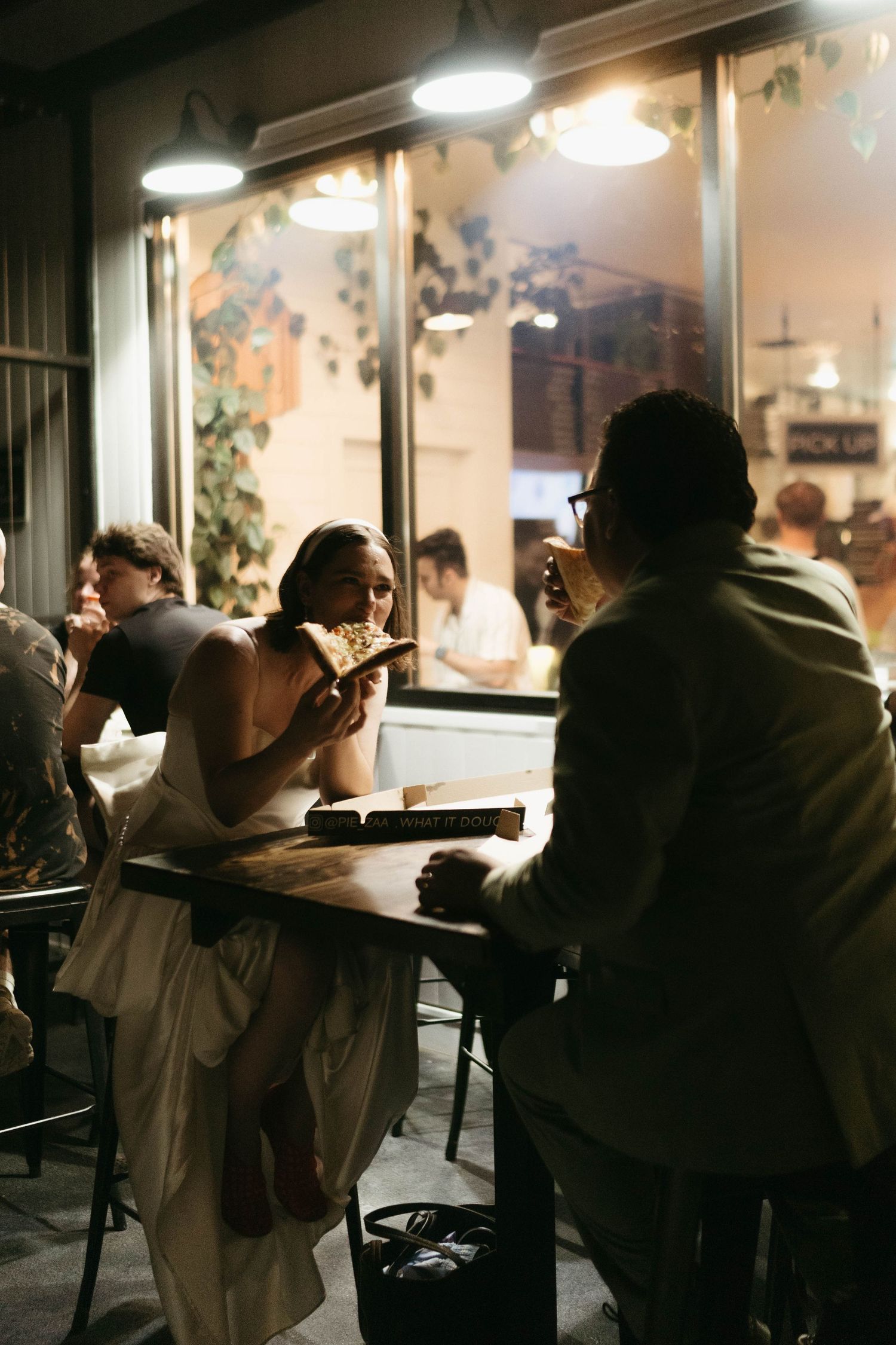 Dark and moody scene of people dining at tables in a dimly lit restaurant interior.