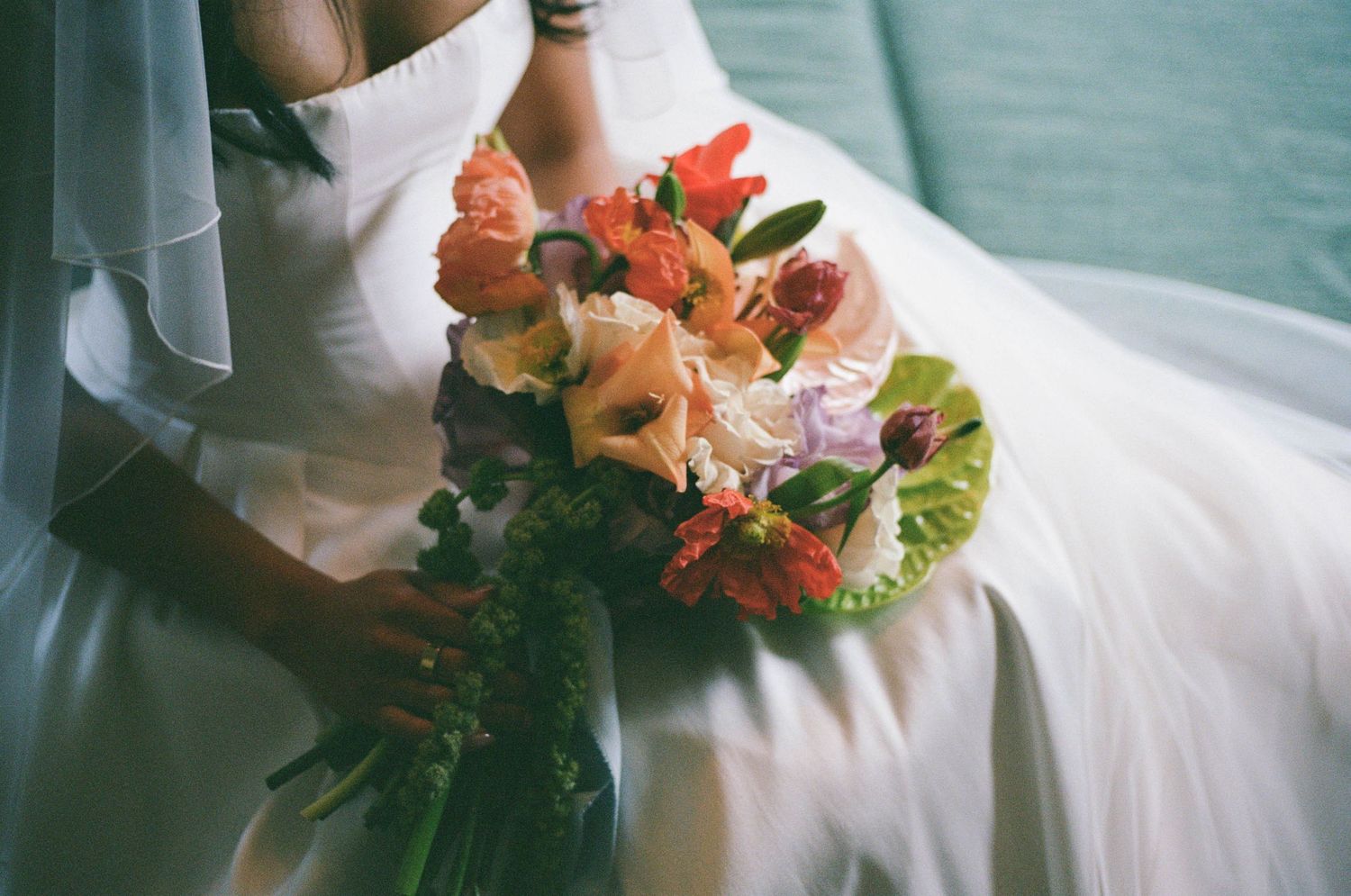 Close-up details of a bridal bouquet with vibrant orange and pink flowers.