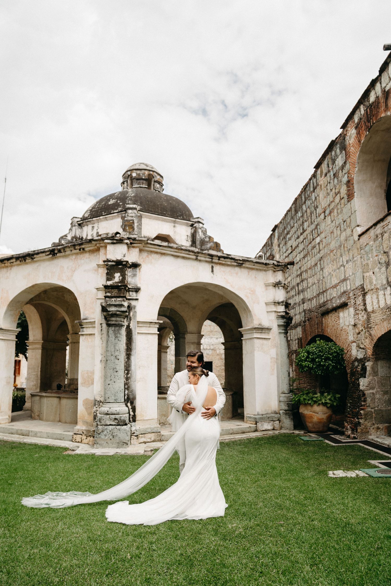 A wedding photo in front of a historic domed building with white arches and columns.