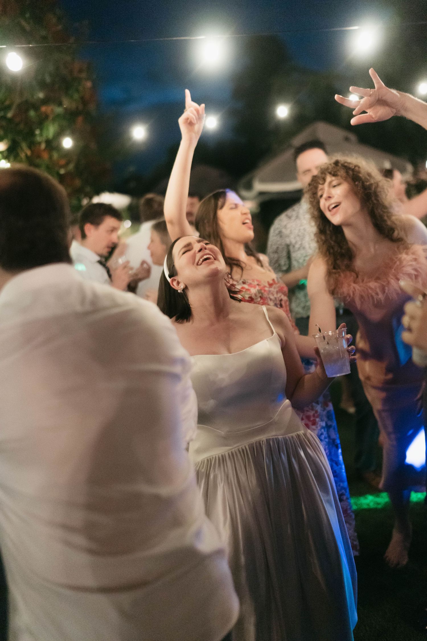 Guests dancing beneath string lights at an outdoor evening celebration.