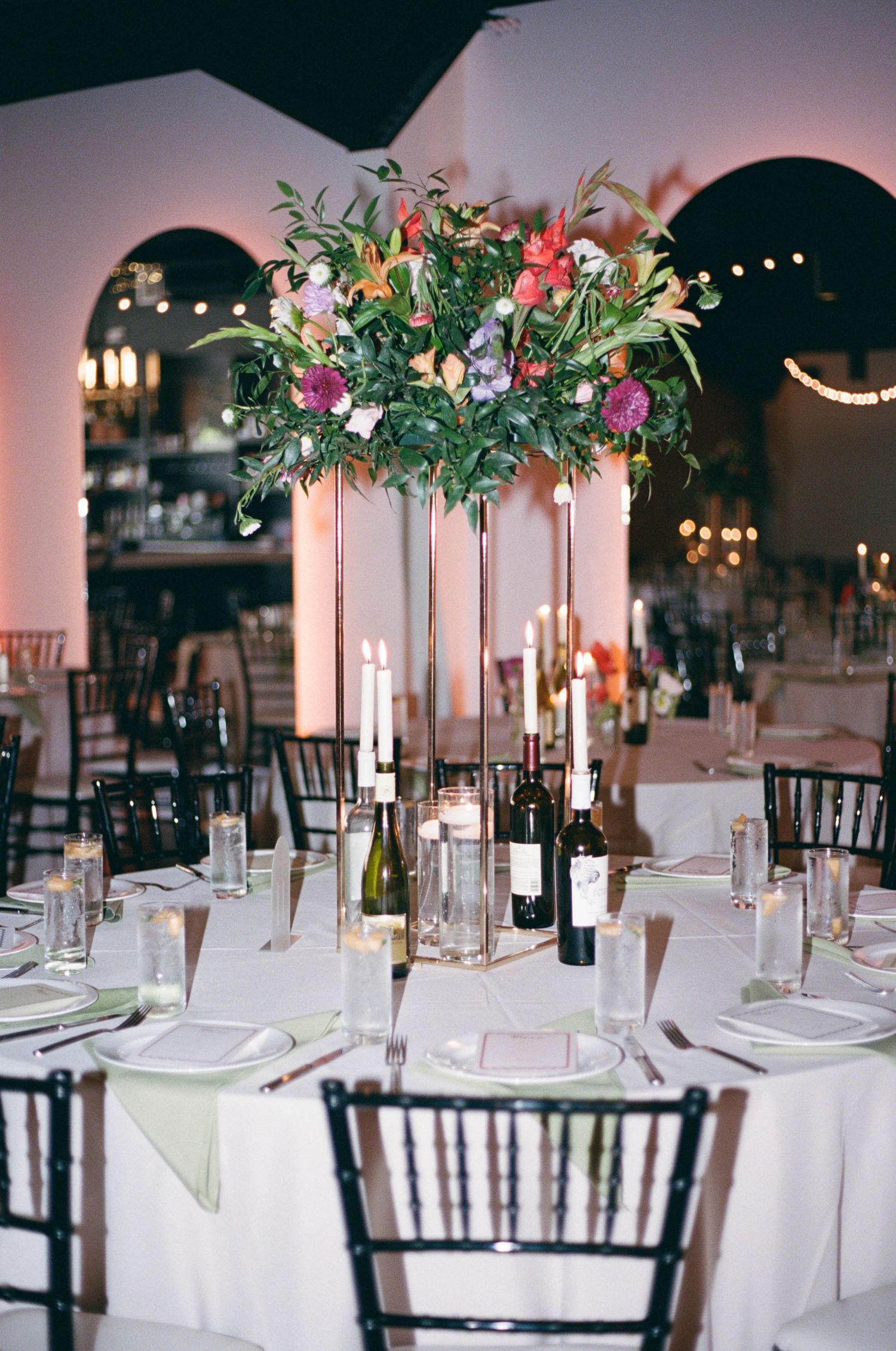 Elegant wedding reception tables decorated with tall floral centerpieces and white linens.