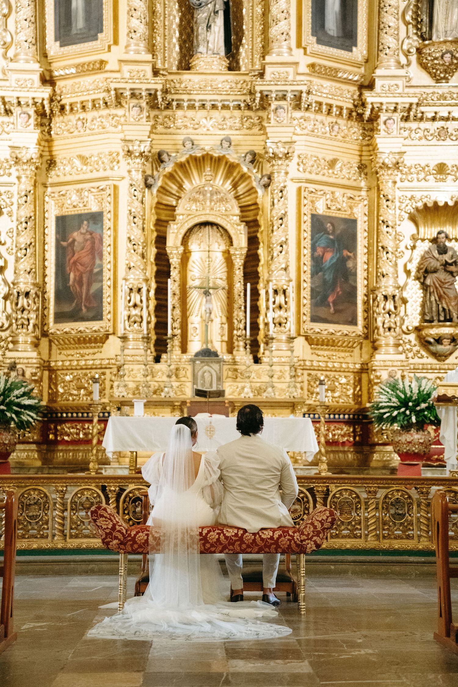 Wedding couple photographed in ornate golden church altar with baroque details.