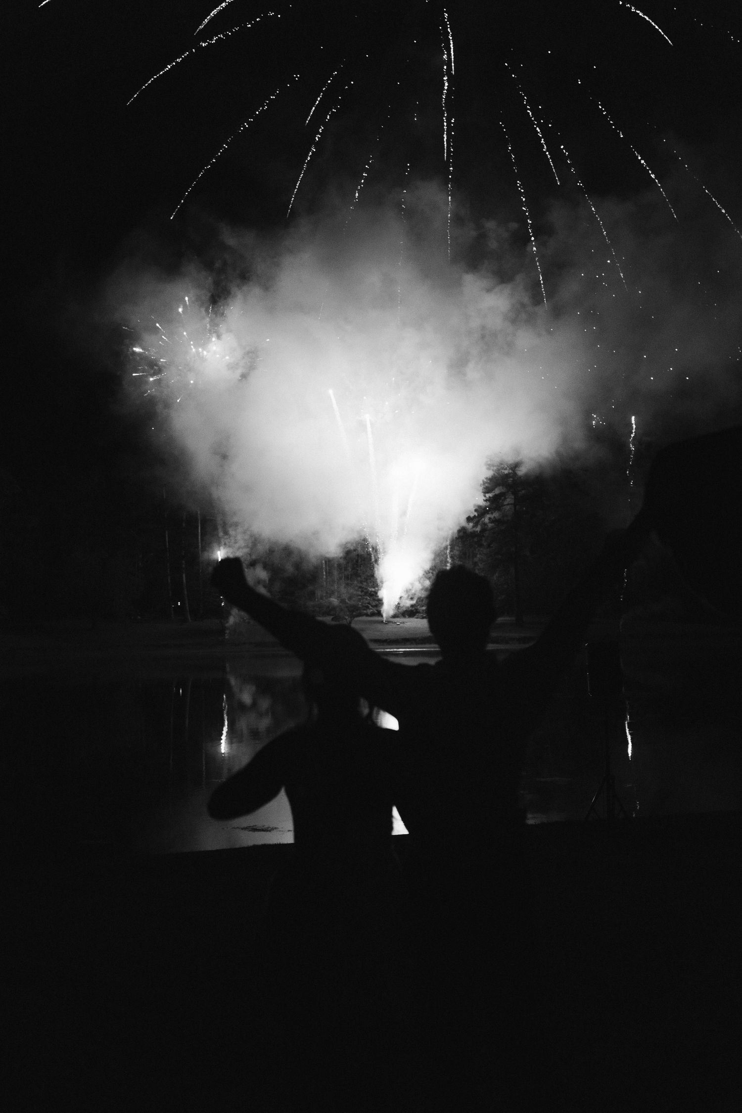 Silhouetted couple watching a stunning fireworks display lighting up the night sky in black and white.