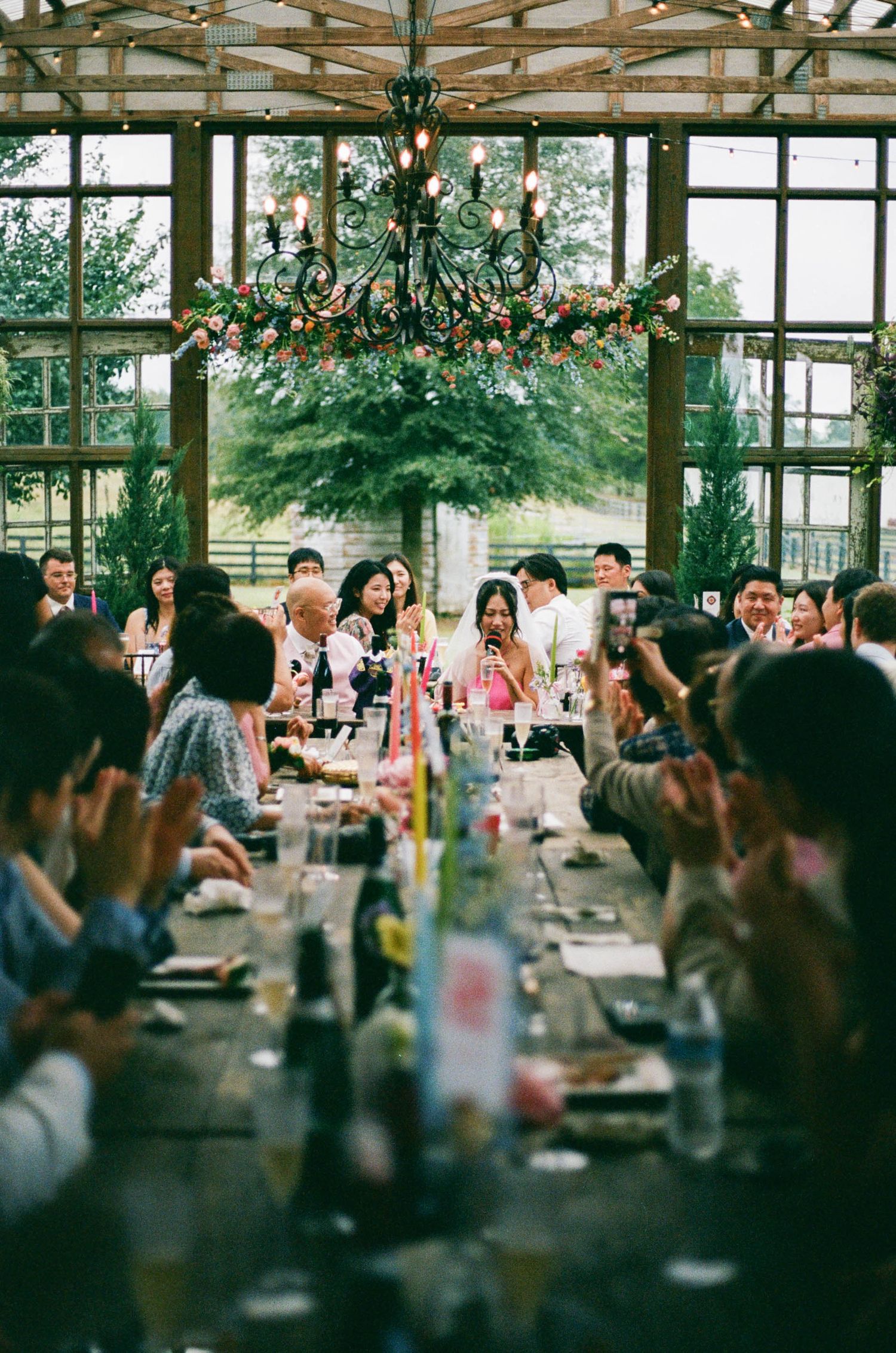 Wedding reception in a rustic venue with exposed wooden beams and hanging lights.