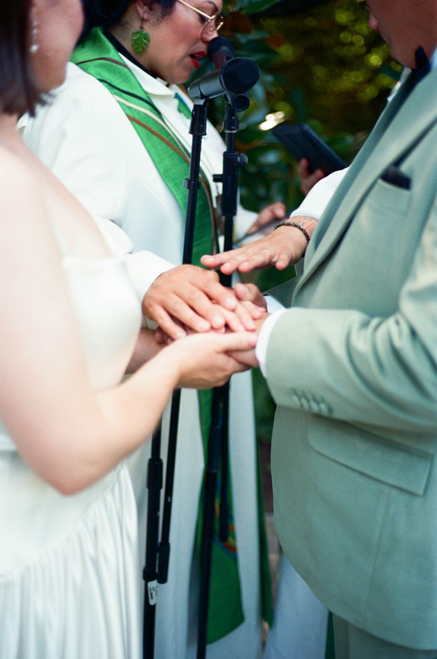 Close-up of hands during a ring exchange ceremony at an outdoor wedding.