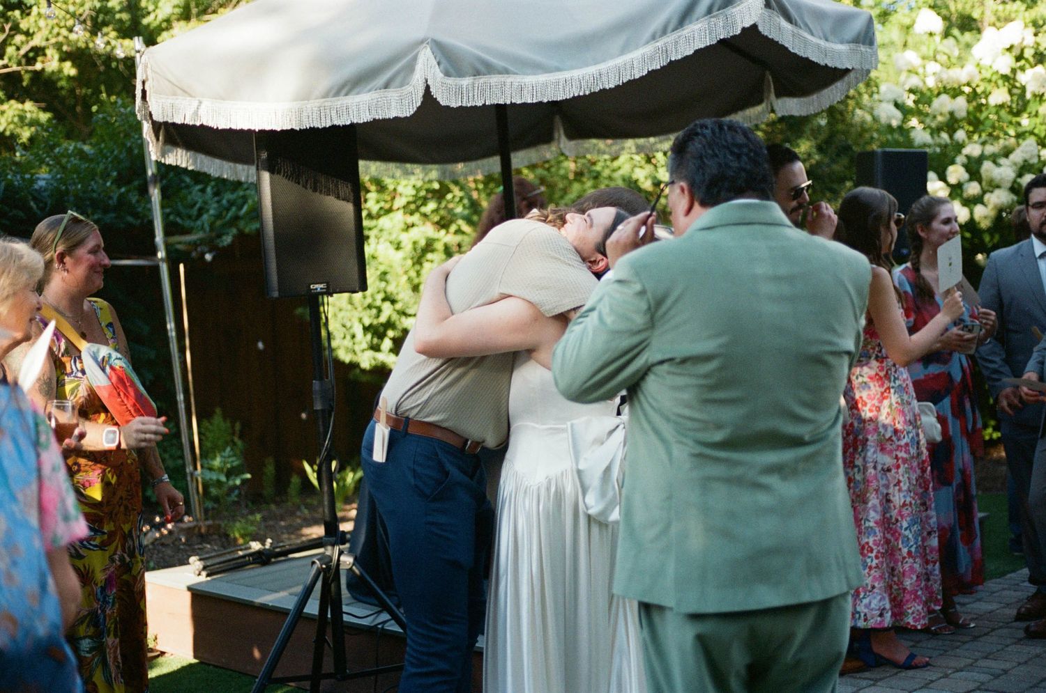 Emotional embrace during outdoor wedding reception under white canopy.