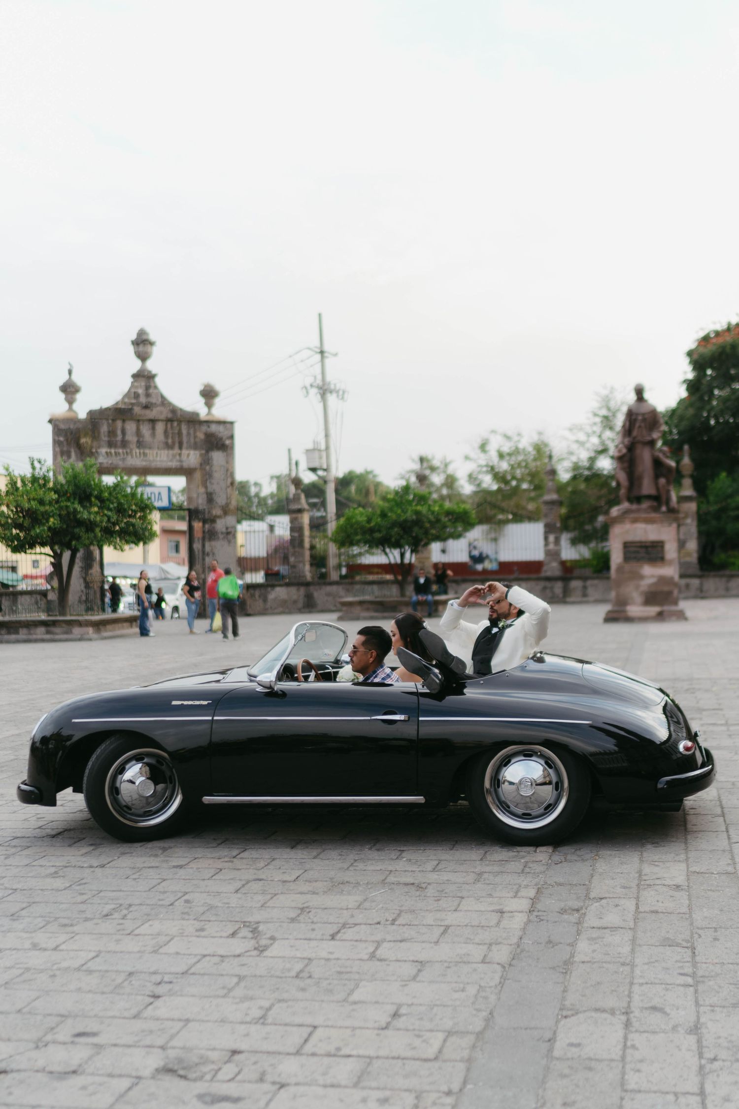 Classic black convertible car parked in a historic stone plaza.