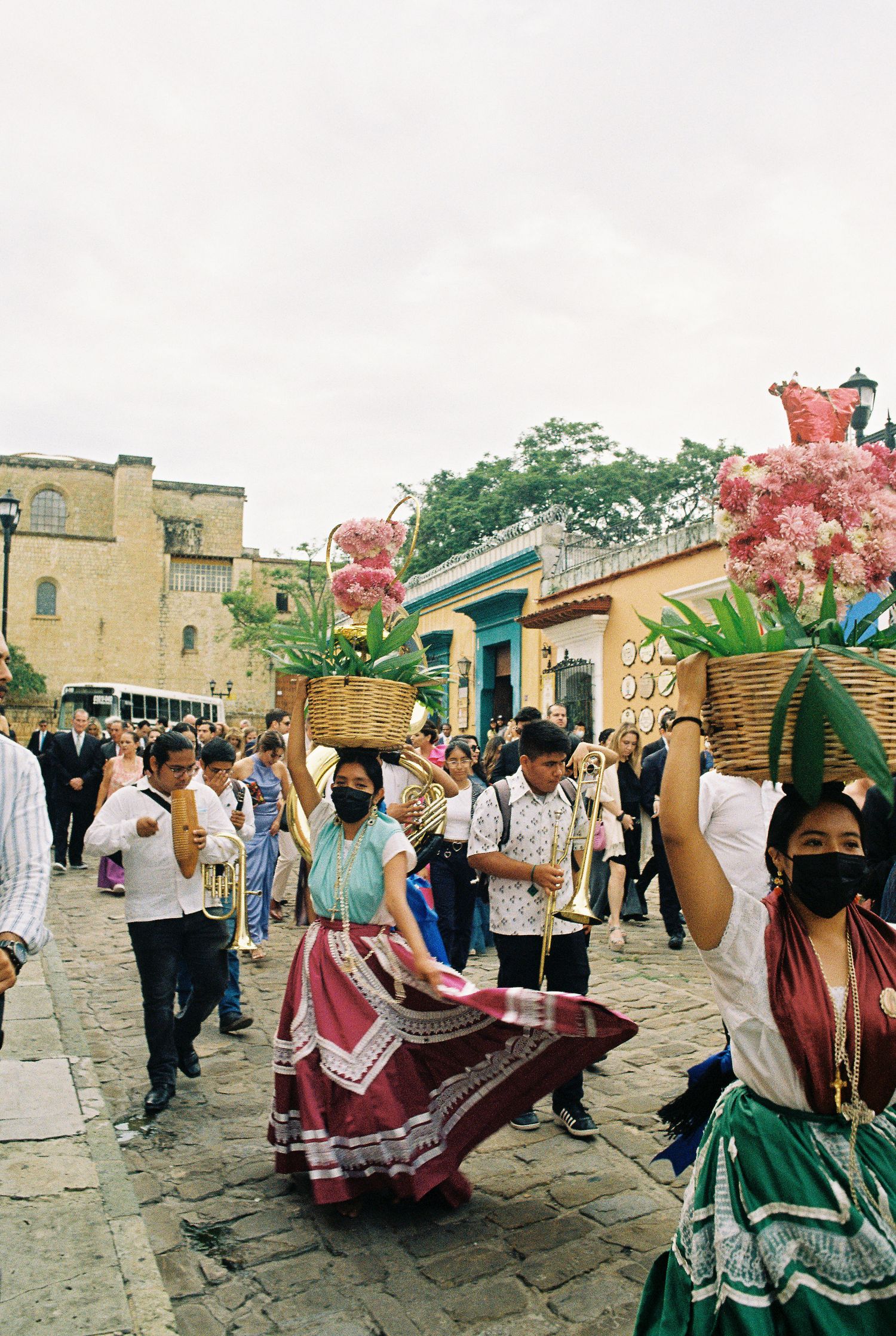 Traditional Mexican dancers in flowing dresses perform on cobblestone streets during a wedding celebration.