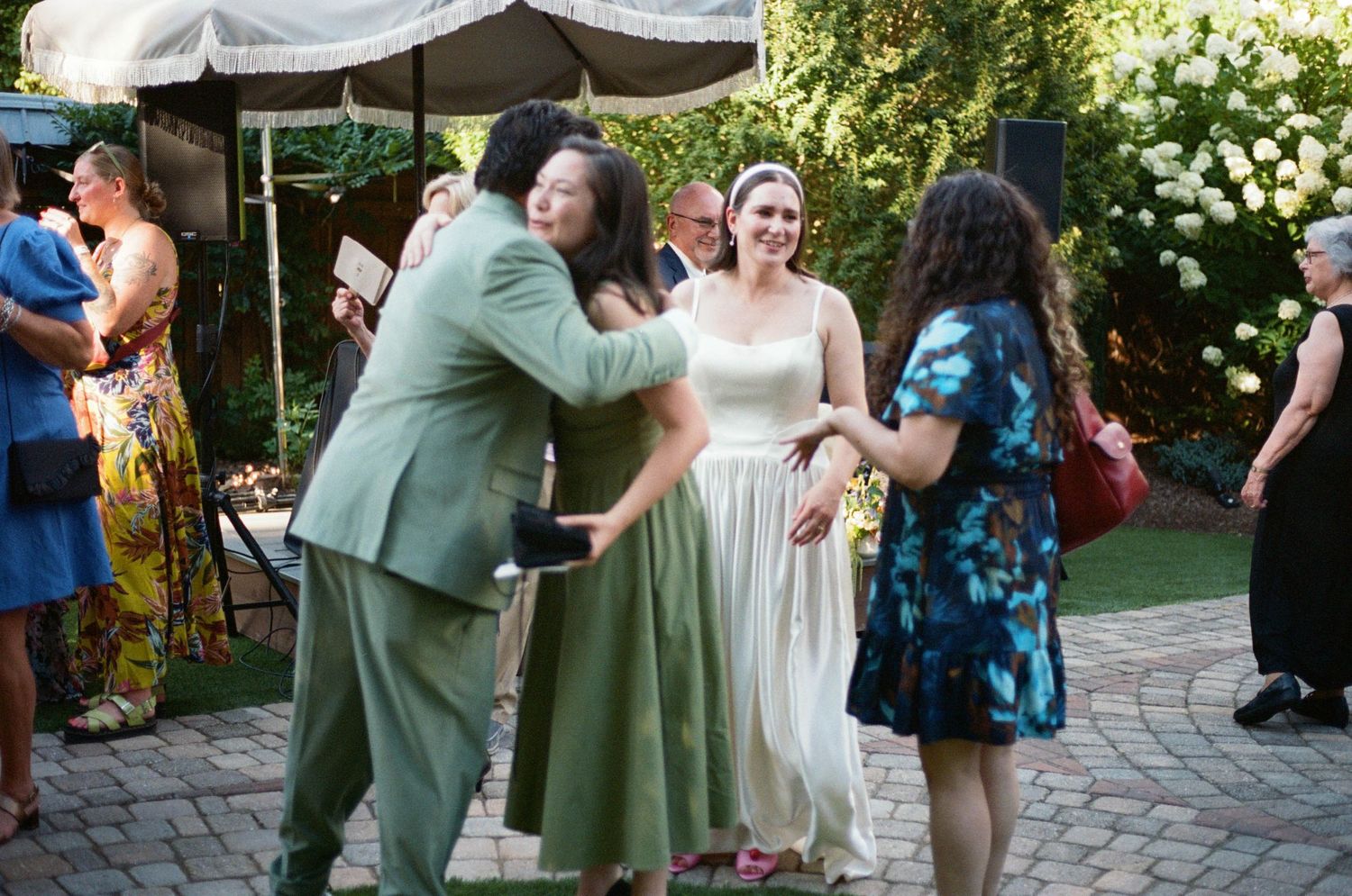 Wedding guests dancing and celebrating on a brick patio during outdoor reception.