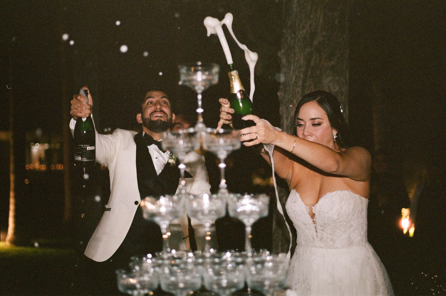A celebratory moment pouring champagne into a tower of crystal glasses at an elegant wedding reception.