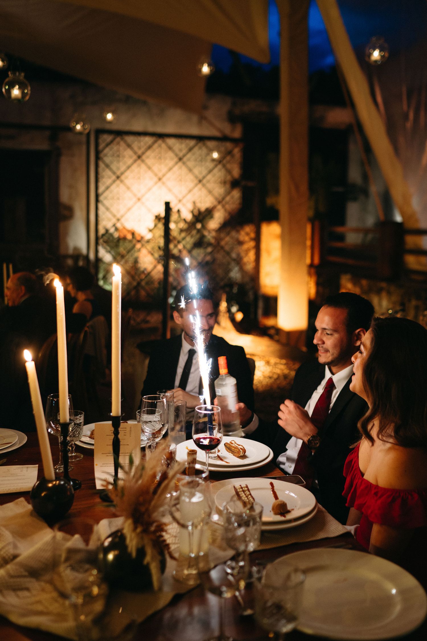 Candlelit wedding reception dinner with elegant table settings and ambient lighting.