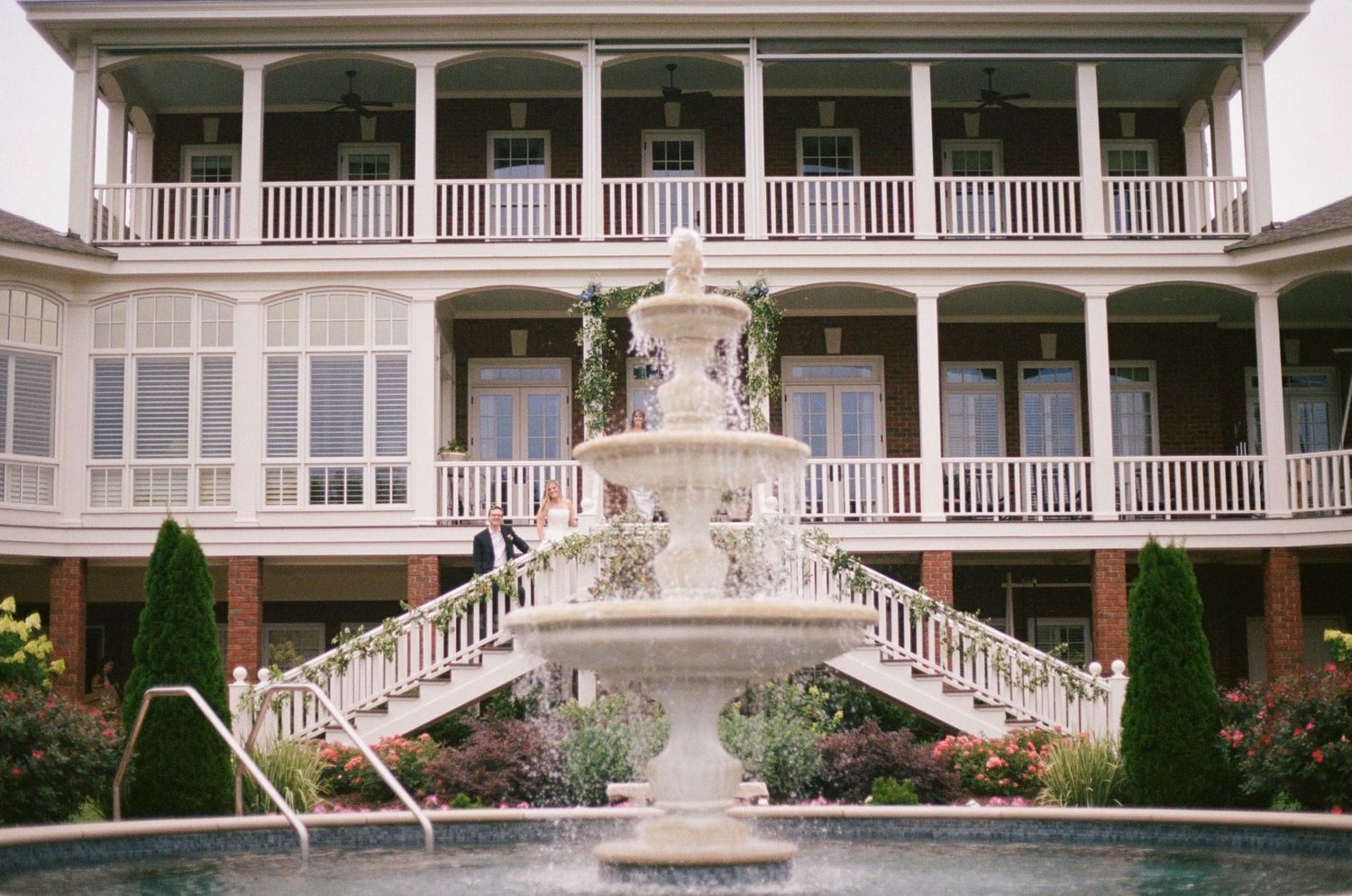 Grand Southern estate with white fountain, brick courtyard, and double wraparound porches at a wedding venue.