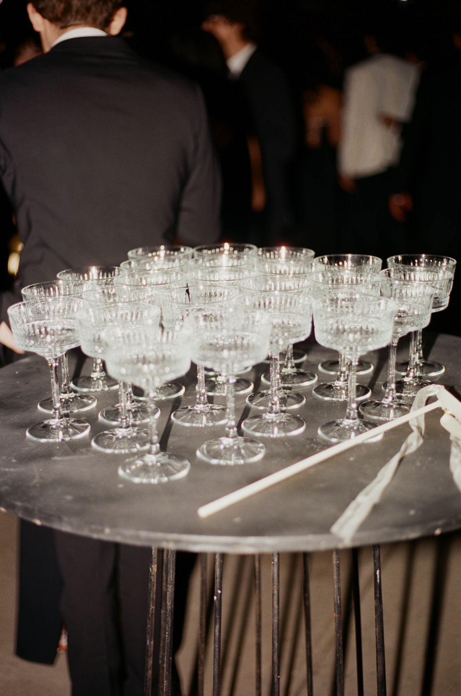 Rows of elegant champagne glasses arranged on a dark surface at an event.