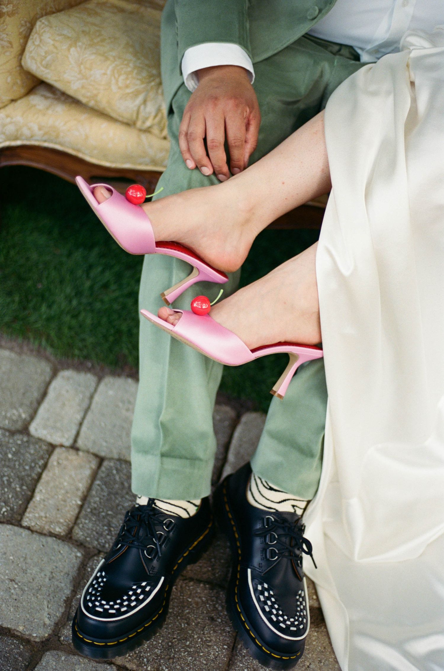 Contrasting footwear showing black creepers and pink heels on stone pavement.