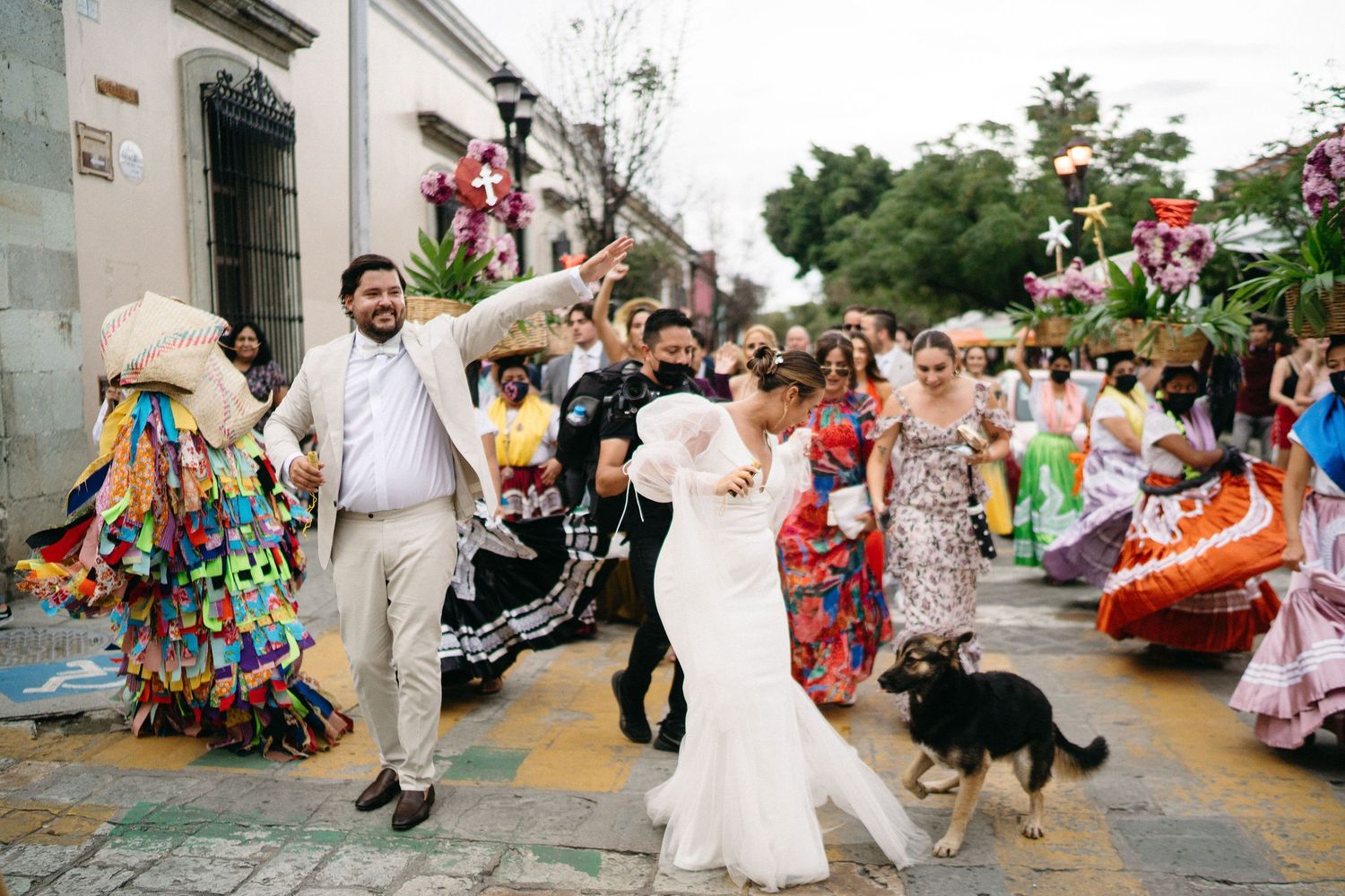 Wedding party dances joyfully in a line during outdoor celebration with colorful decorations and festive atmosphere.
