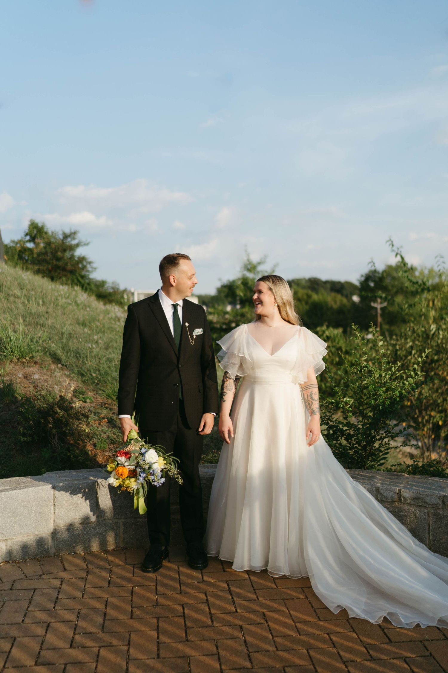 Bride and groom sharing candid moments on a brick terrace during sunset.