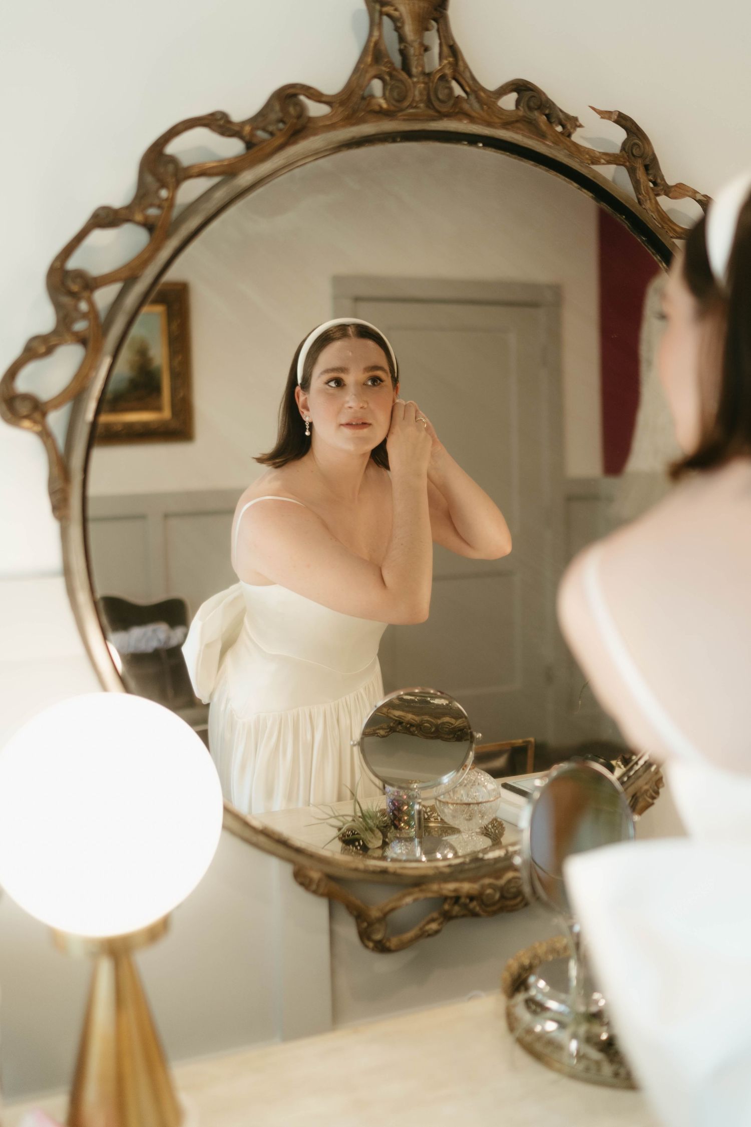 Elegant vintage mirror reflects bridal preparations in soft natural light.