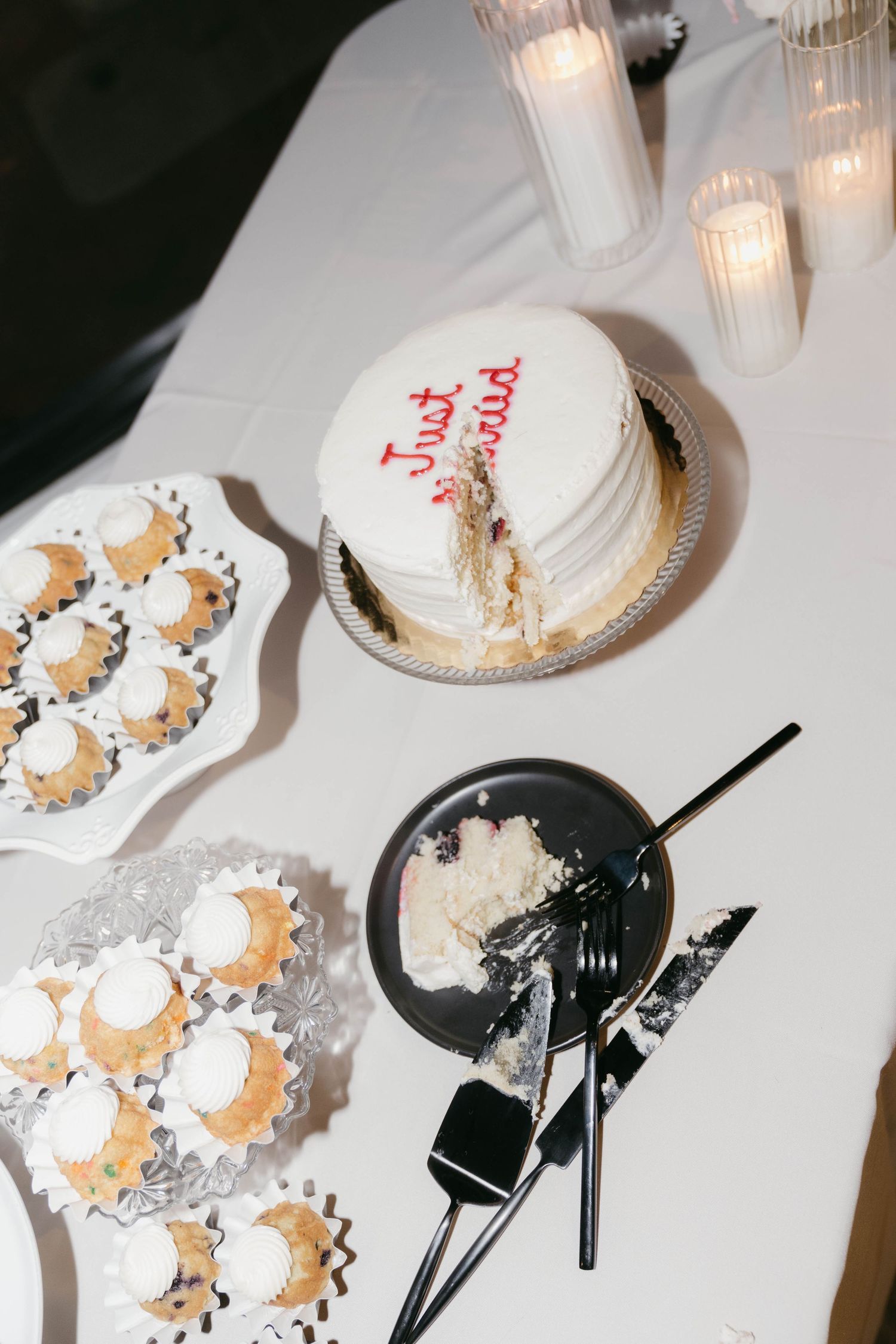 Wedding dessert table with white frosted cakes and mini pastries.