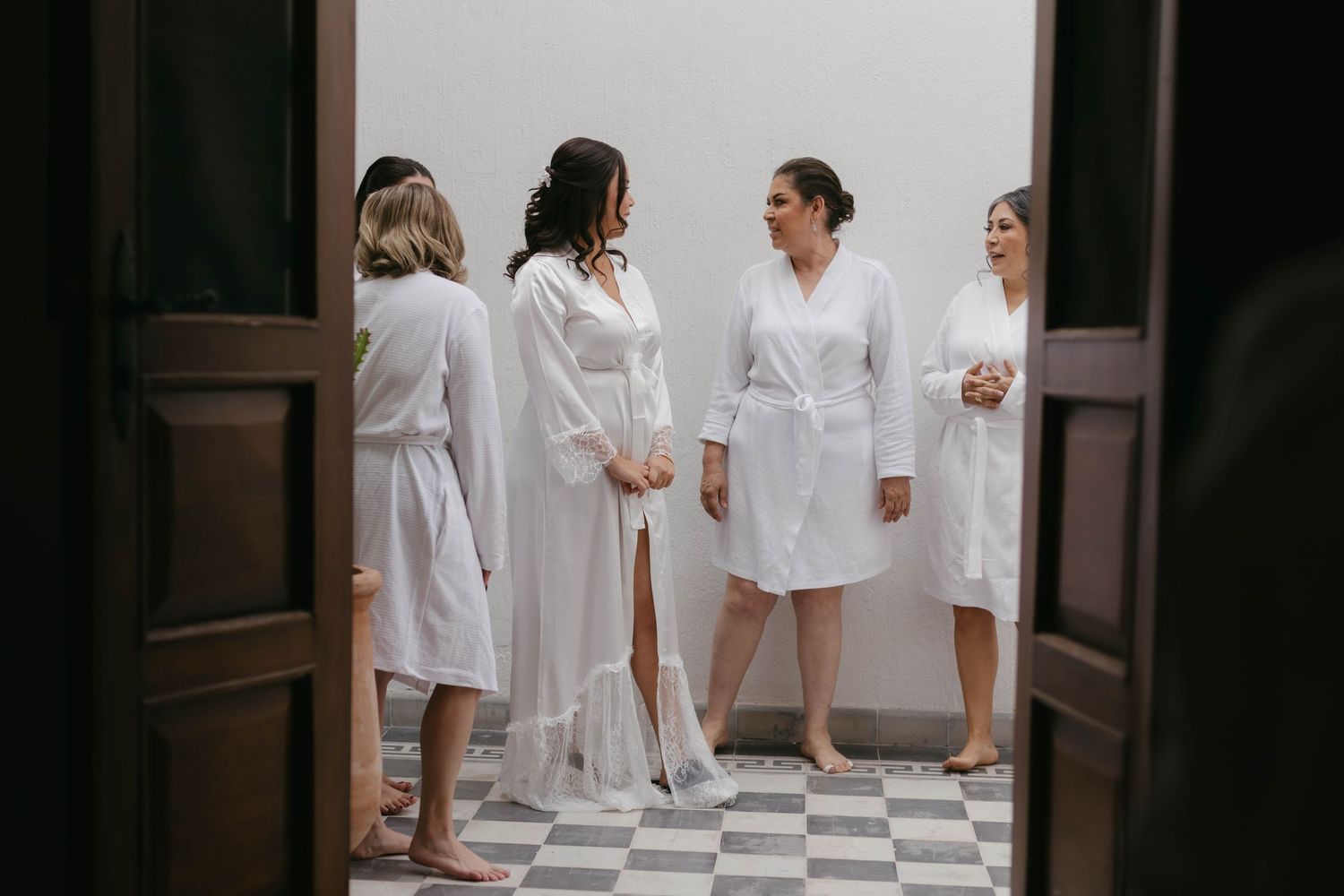 Group wearing white robes gathered in a minimalist room with white walls.