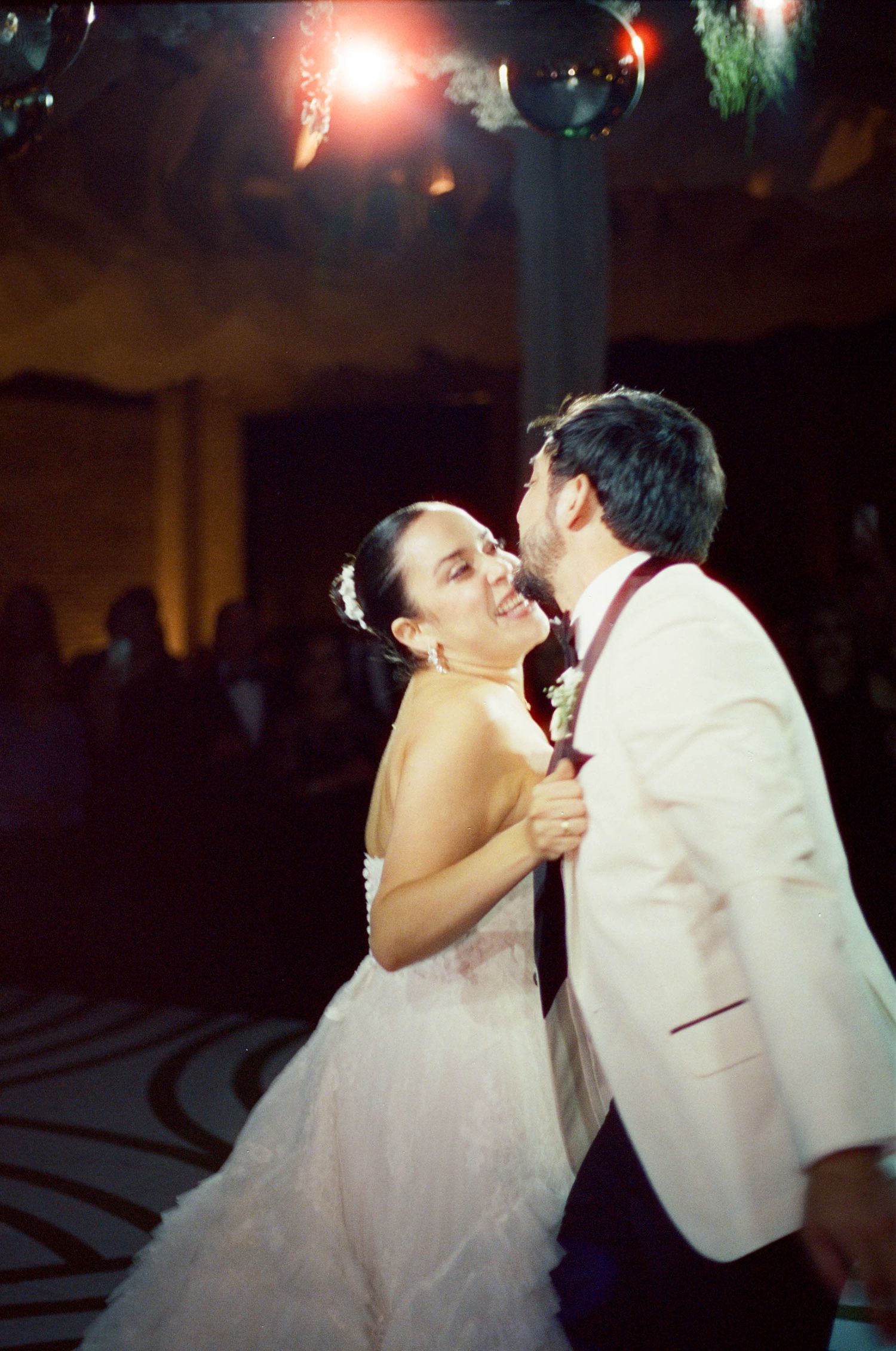 Bride and groom share an intimate dance moment under dramatic lighting at their reception.