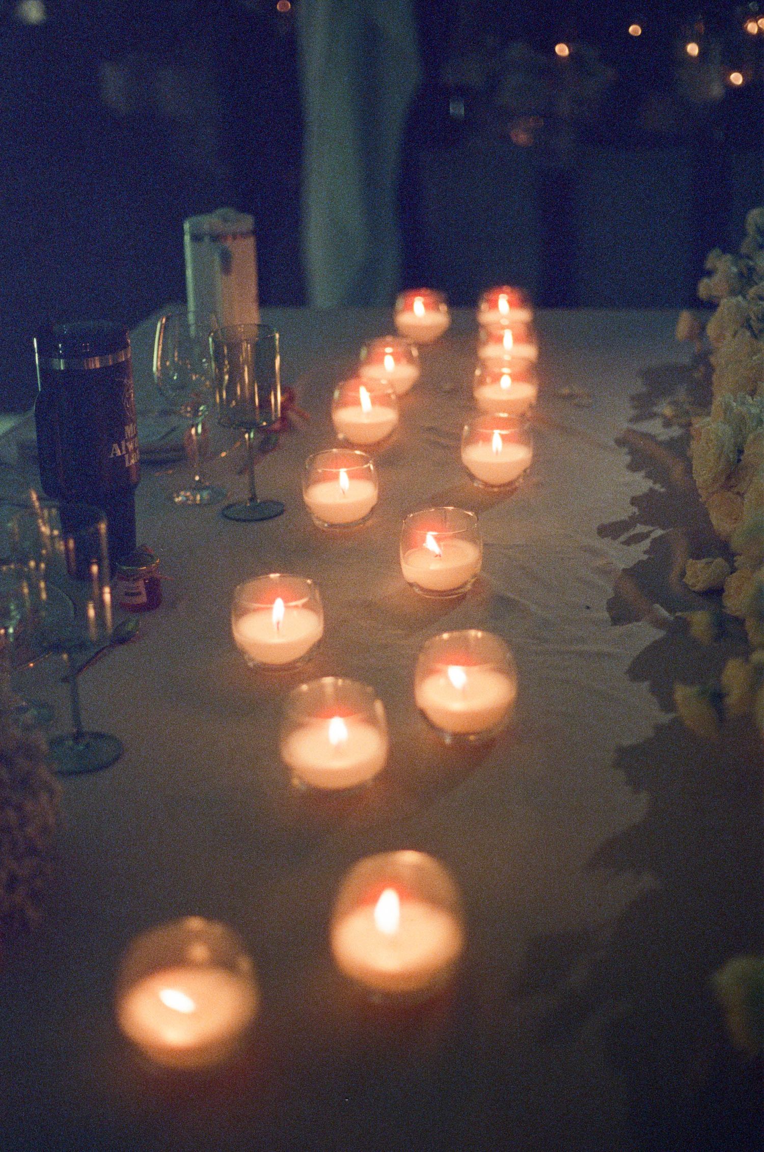 Tea light candles create a romantic ambiance on a decorated table at an evening event.