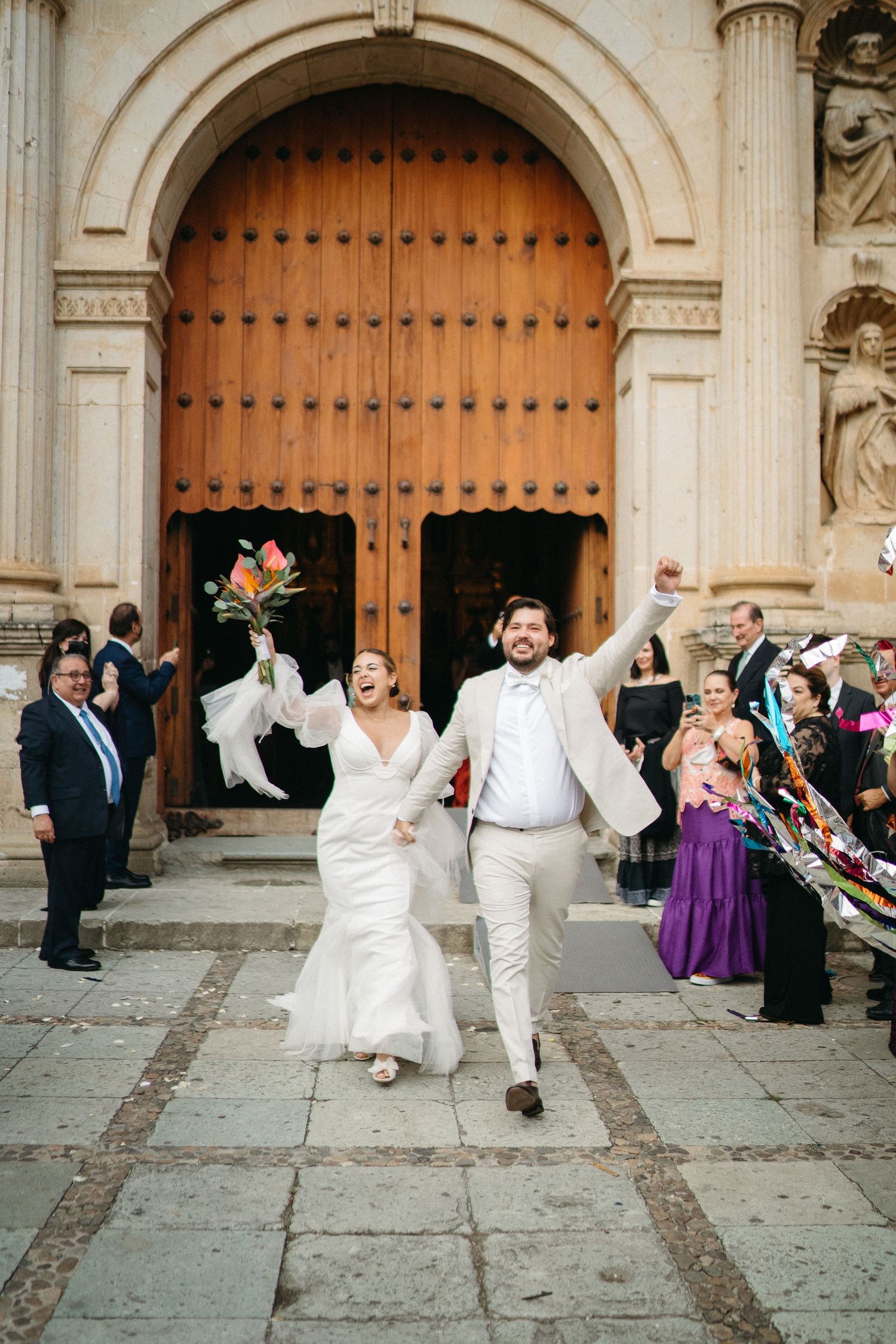 Sequence of newlyweds dancing and celebrating in front of ornate church doors with guests watching.