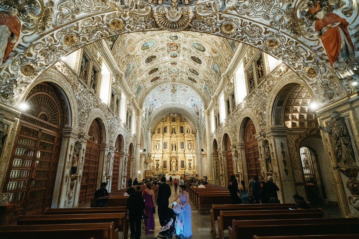 Panoramic view of an elaborately decorated church interior with baroque ceiling frescoes.