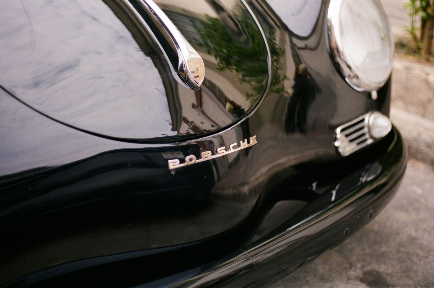 Close-up detail of a black vintage Porsche's front end showing the classic chrome badge.