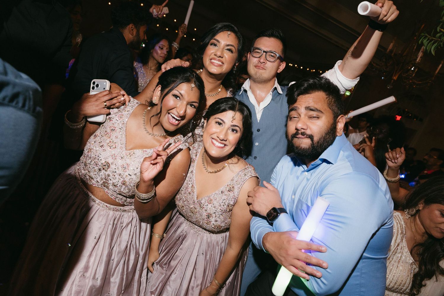 Group of friends celebrating at a wedding reception, posing and dancing together in festive attire.