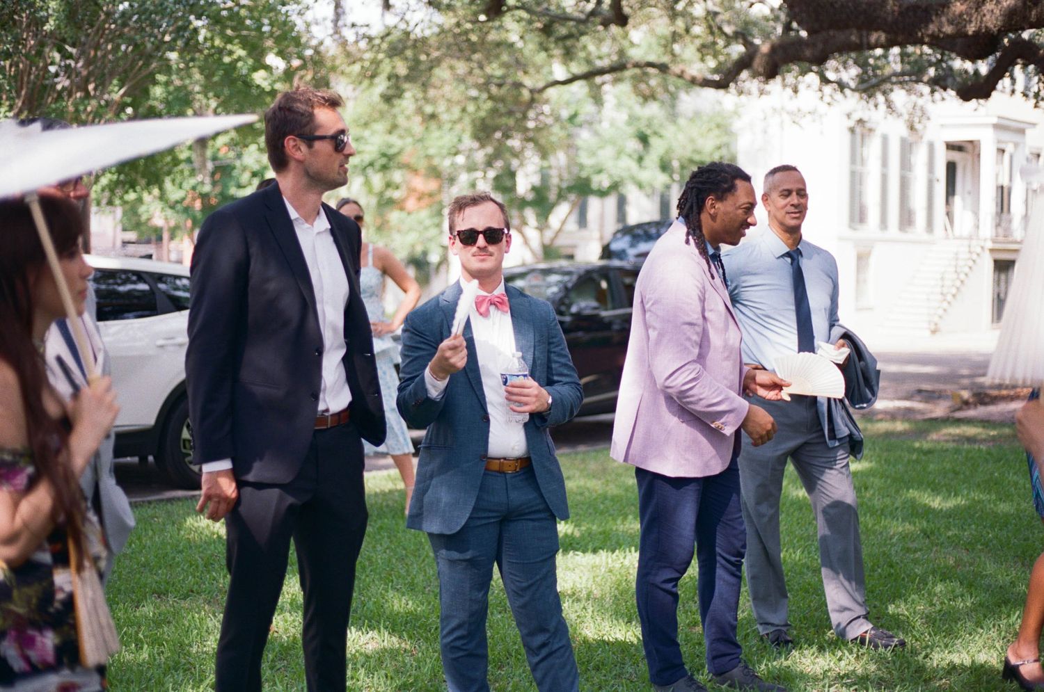 Casual outdoor wedding scene with guests socializing on a grassy lawn.