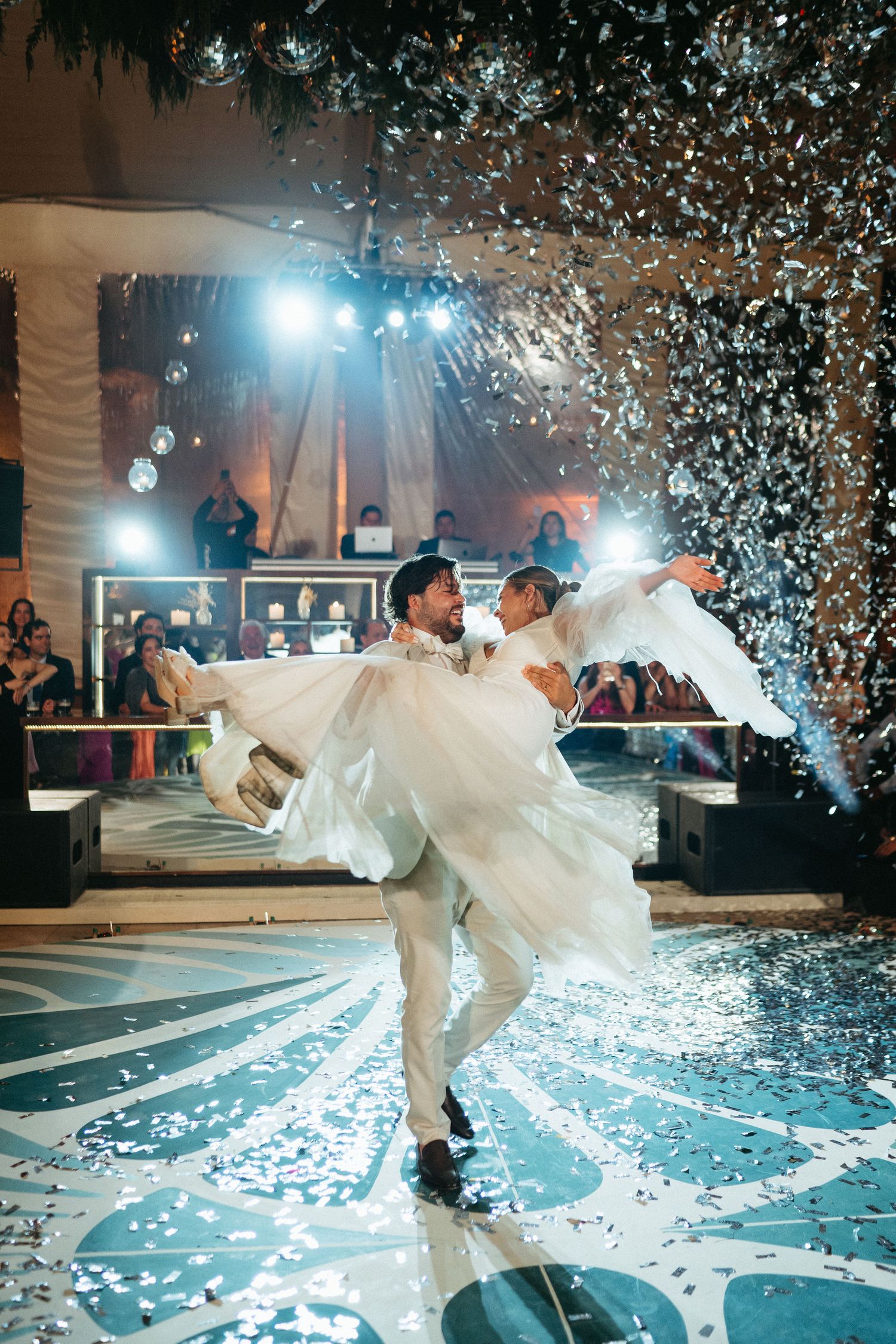 Couple performs first dance under falling confetti at wedding reception.