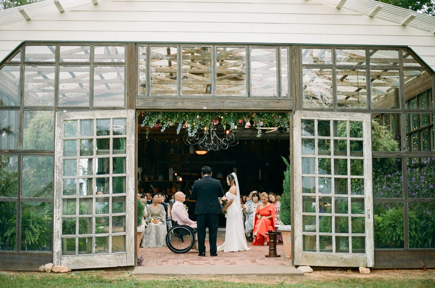 Wedding ceremony setup in a glass-walled conservatory with natural lighting.
