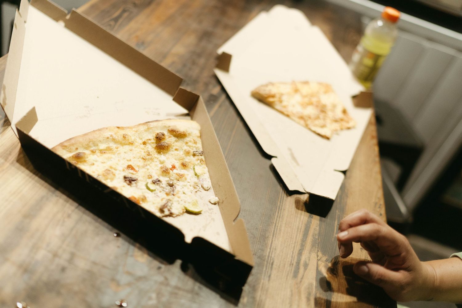 Close-up of hands handling paper items on a wooden table surface.